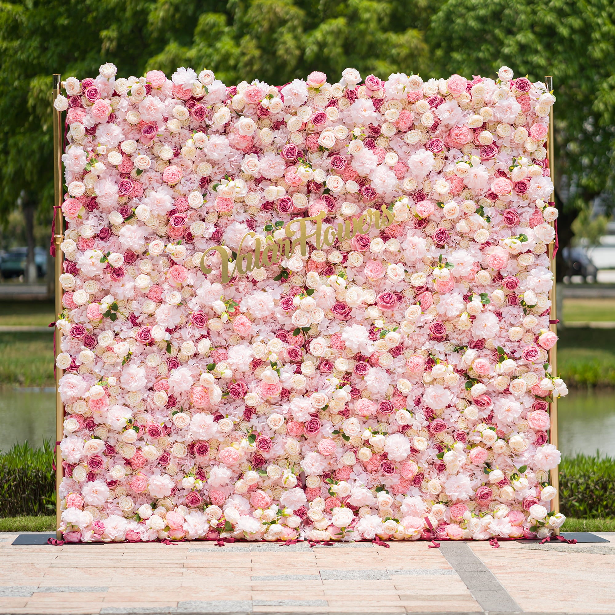 This photo from ValarFlowers showcases a large, lush floral backdrop. It is densely filled with an array of pink and white roses and peonies, creating a soft and romantic atmosphere. The backdrop is framed by golden poles, adding a touch of elegance. Ideal for weddings, bridal showers, or a “Blossoming Love” - themed event, it serves as a beautiful decorative element, exuding charm and grace.