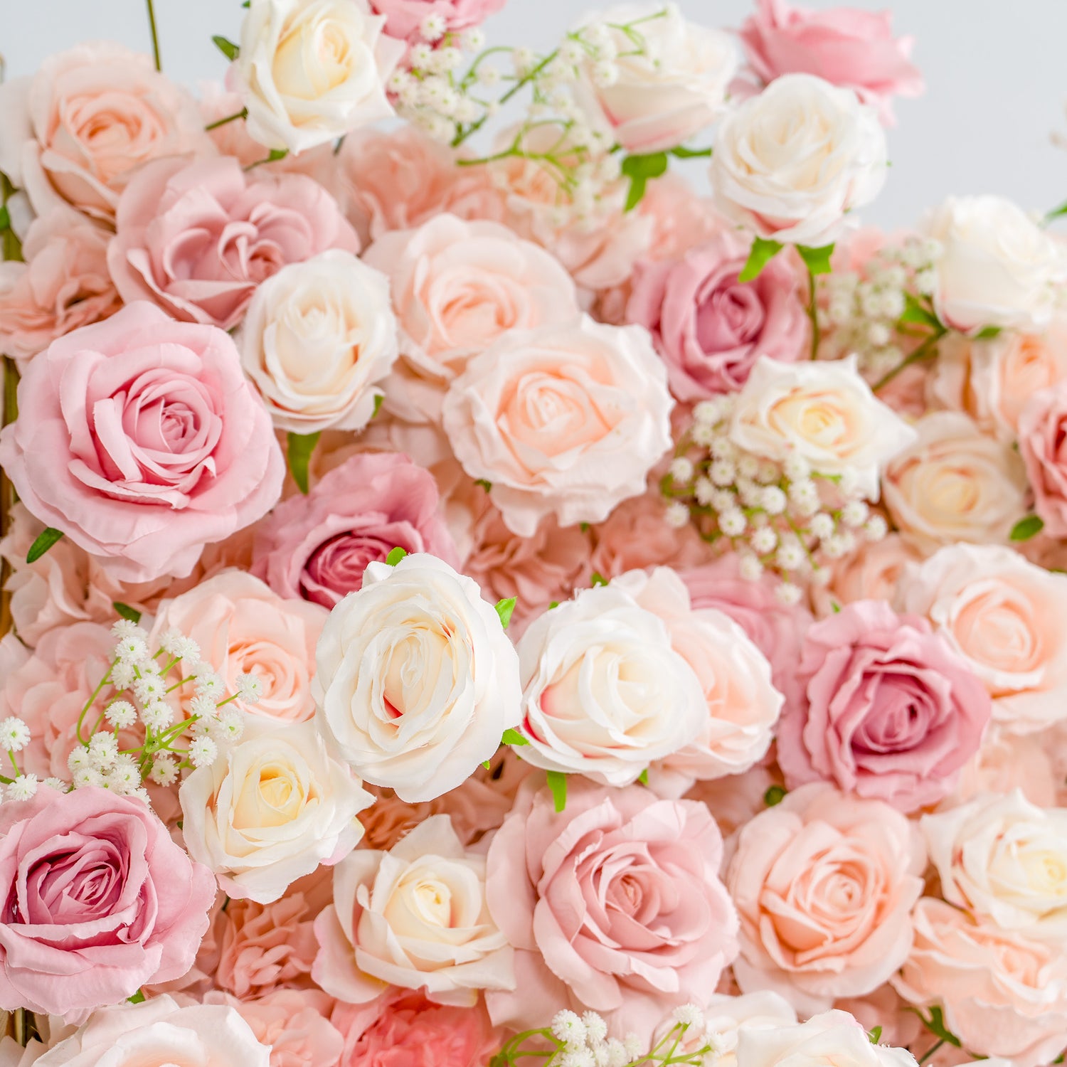 This photo showcases a lush arrangement of roses in soft shades of pink, peach, and white, interspersed with delicate baby&