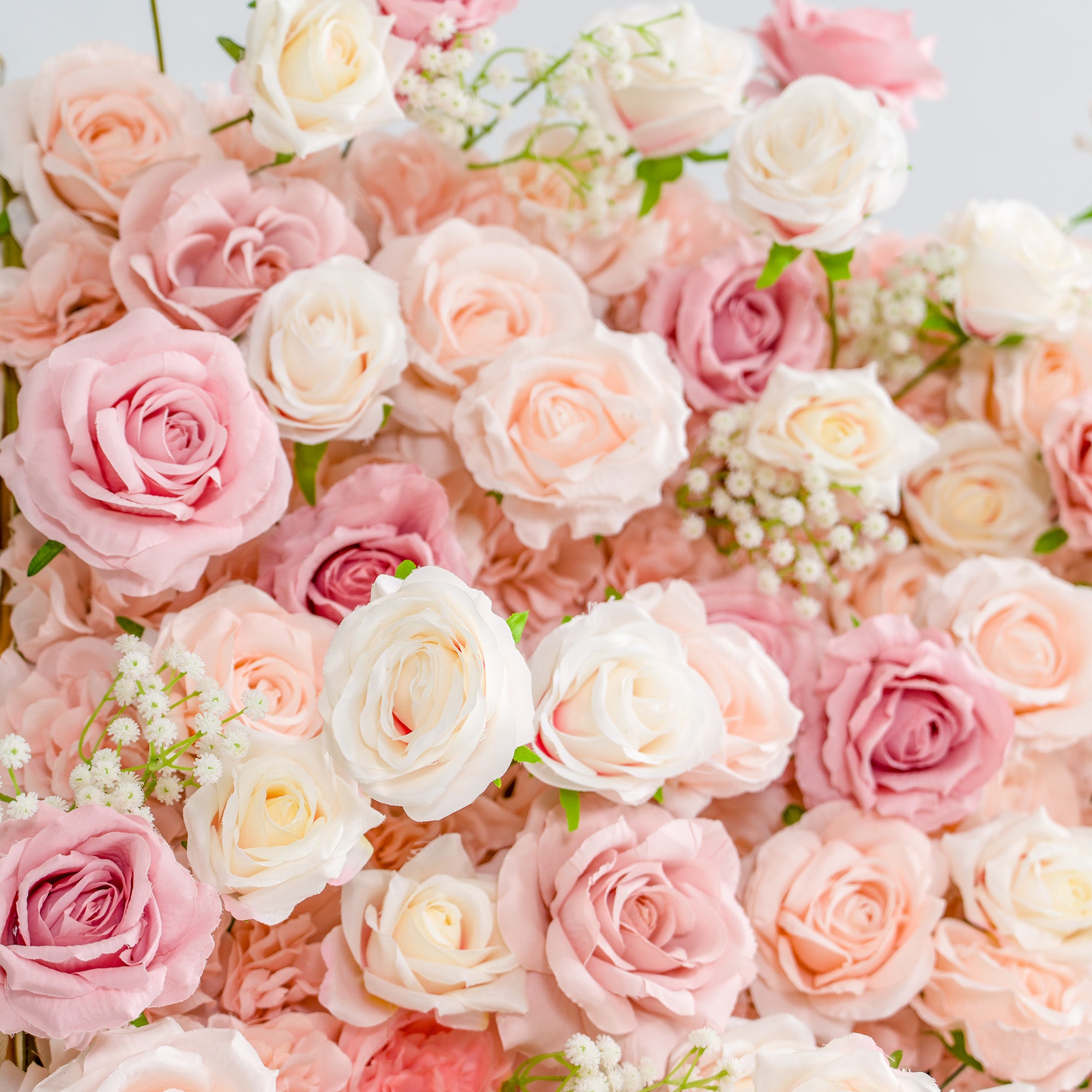 This photo showcases a lush arrangement of roses in soft shades of pink, peach, and white, interspersed with delicate baby&