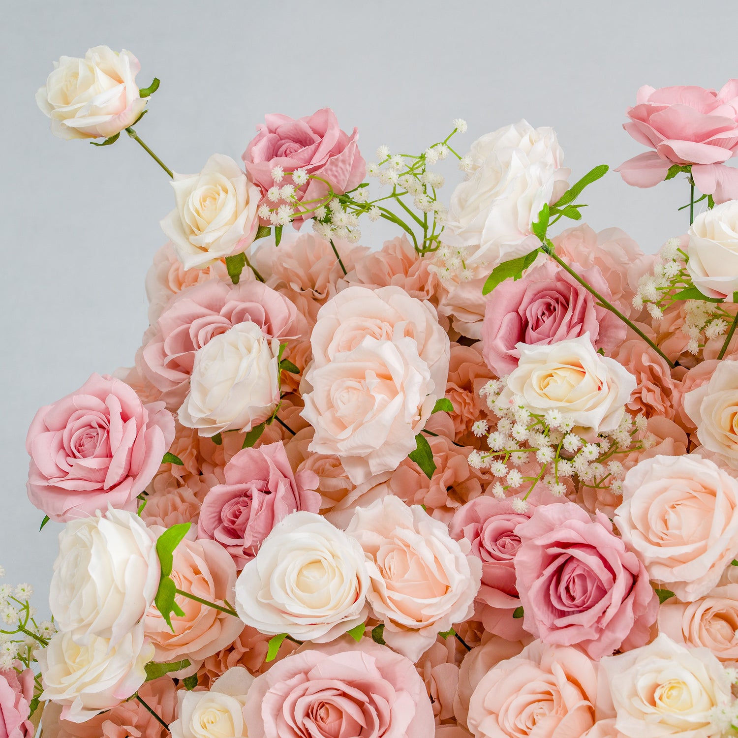 This photo showcases a lush arrangement of roses in soft shades of pink, peach, and white, interspersed with delicate baby&