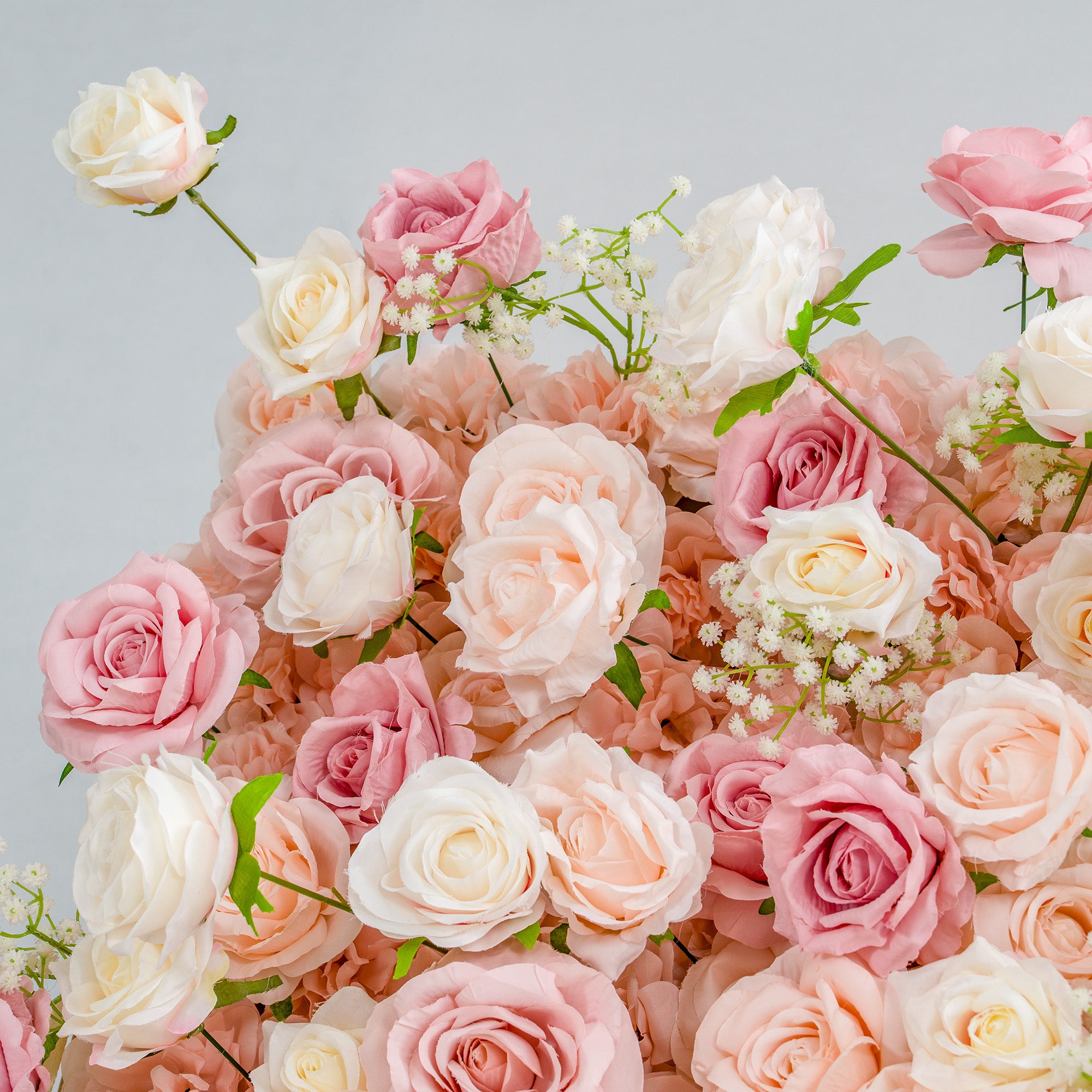 This photo showcases a lush arrangement of roses in soft shades of pink, peach, and white, interspersed with delicate baby&