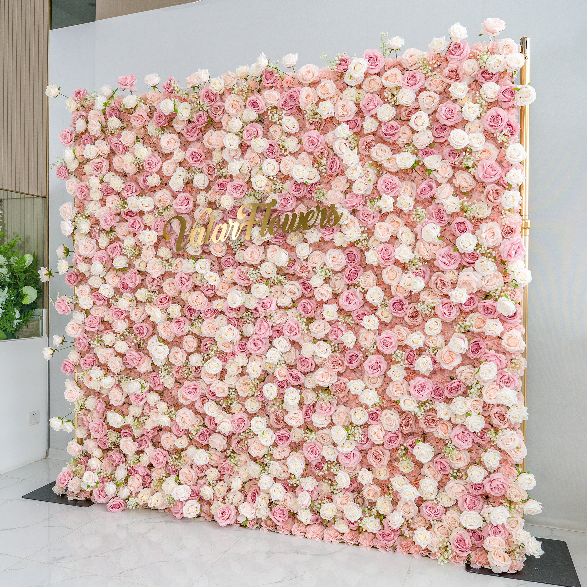 This photo showcases a large floral backdrop densely adorned with pink and white roses, interspersed with delicate baby&