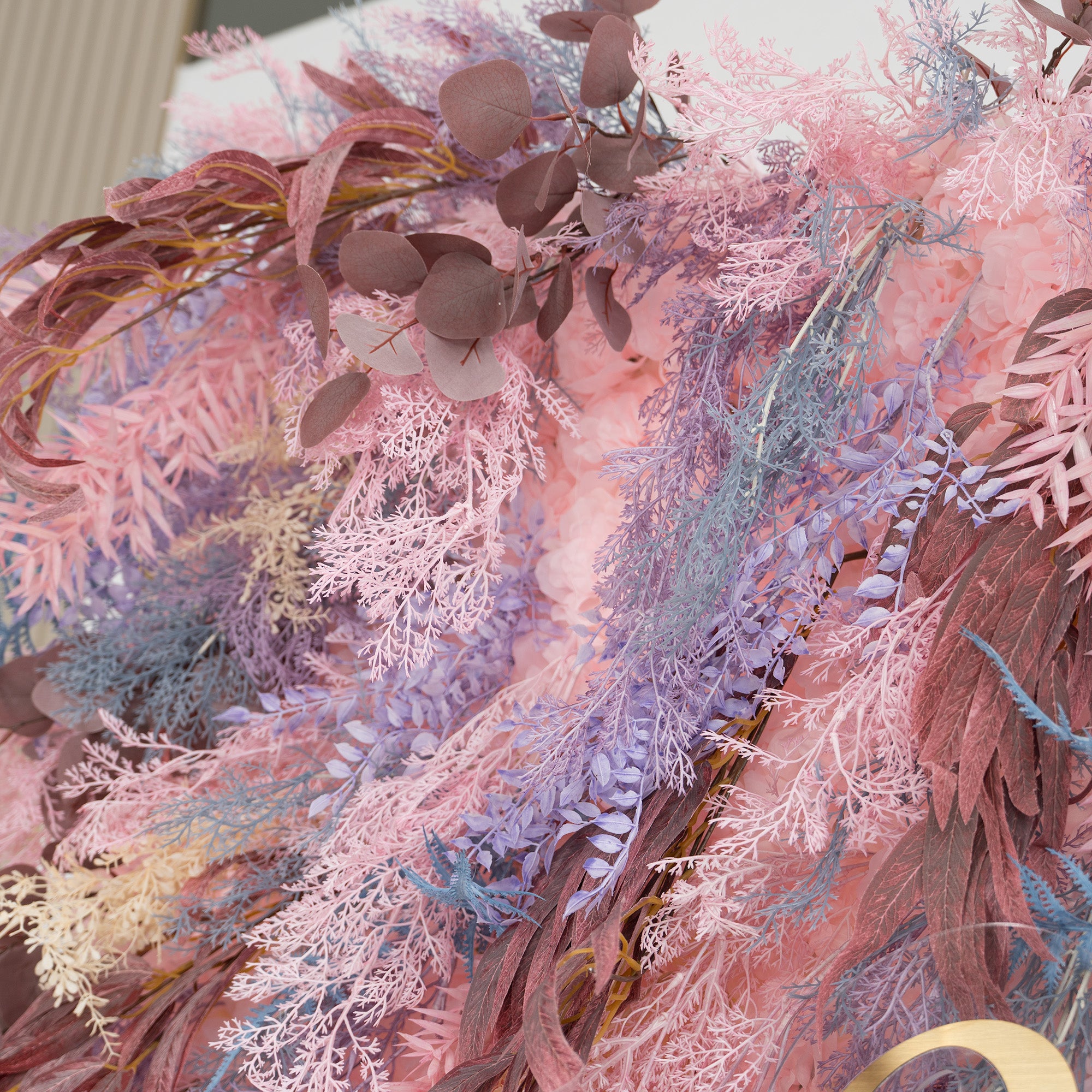 This photo presents a lush, colorful foliage arrangement. It features a mix of fern - like plants in soft pink, purple, and blue hues, along with eucalyptus leaves in earthy brown tones. The rich, pastel color palette creates a dreamy and romantic atmosphere. Ideal for events like weddings, engagement parties, or upscale galas, this backdrop exudes an elegant and whimsical style.