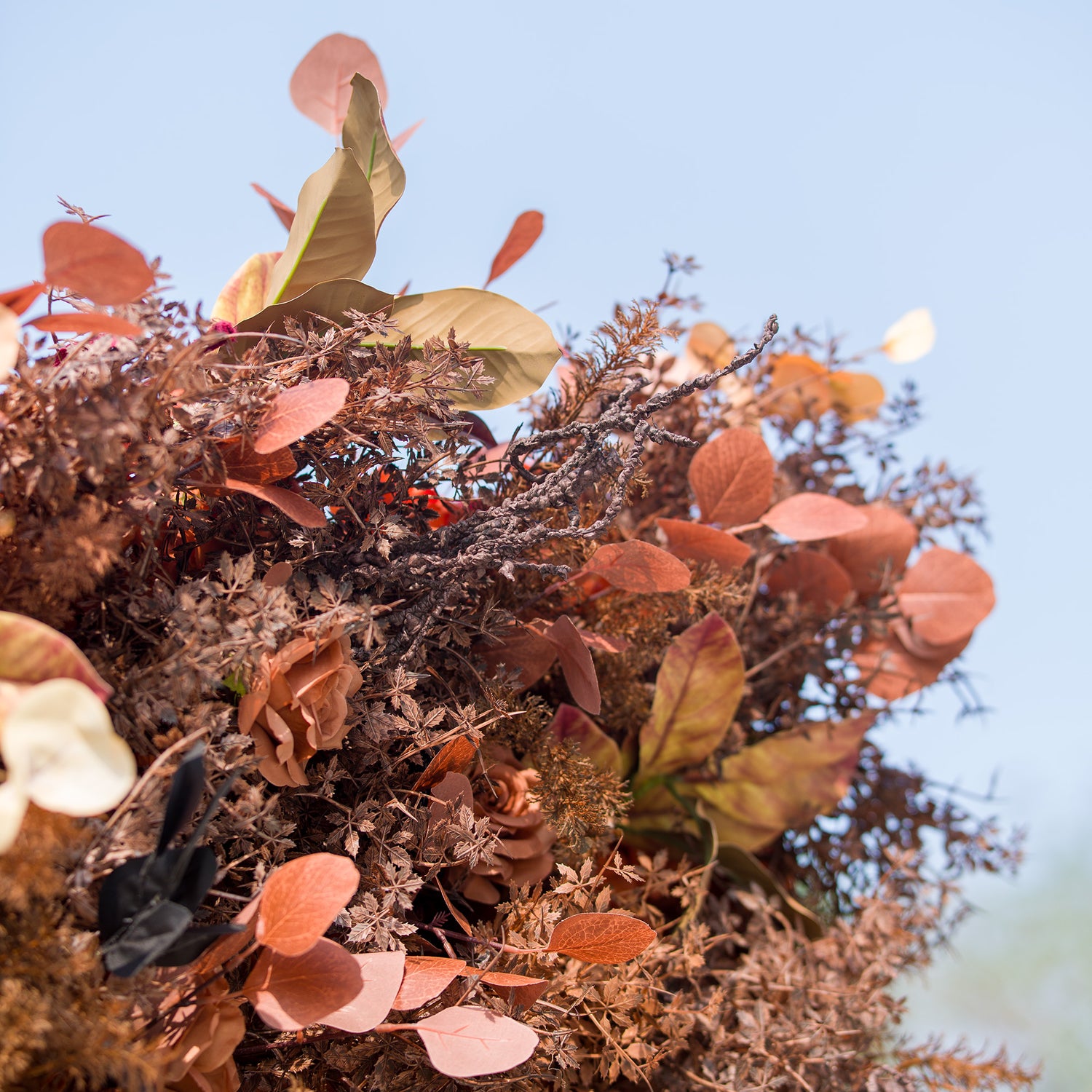 This photo showcases a rich arrangement of autumn - inspired flowers and foliage. The display features roses in warm brown tones, complemented by various dried - look leaves in shades of rust, copper, and orange. Ideal for events like an “Autumn Equinox” celebration or a harvest - themed wedding, it exudes rustic, seasonal charm.