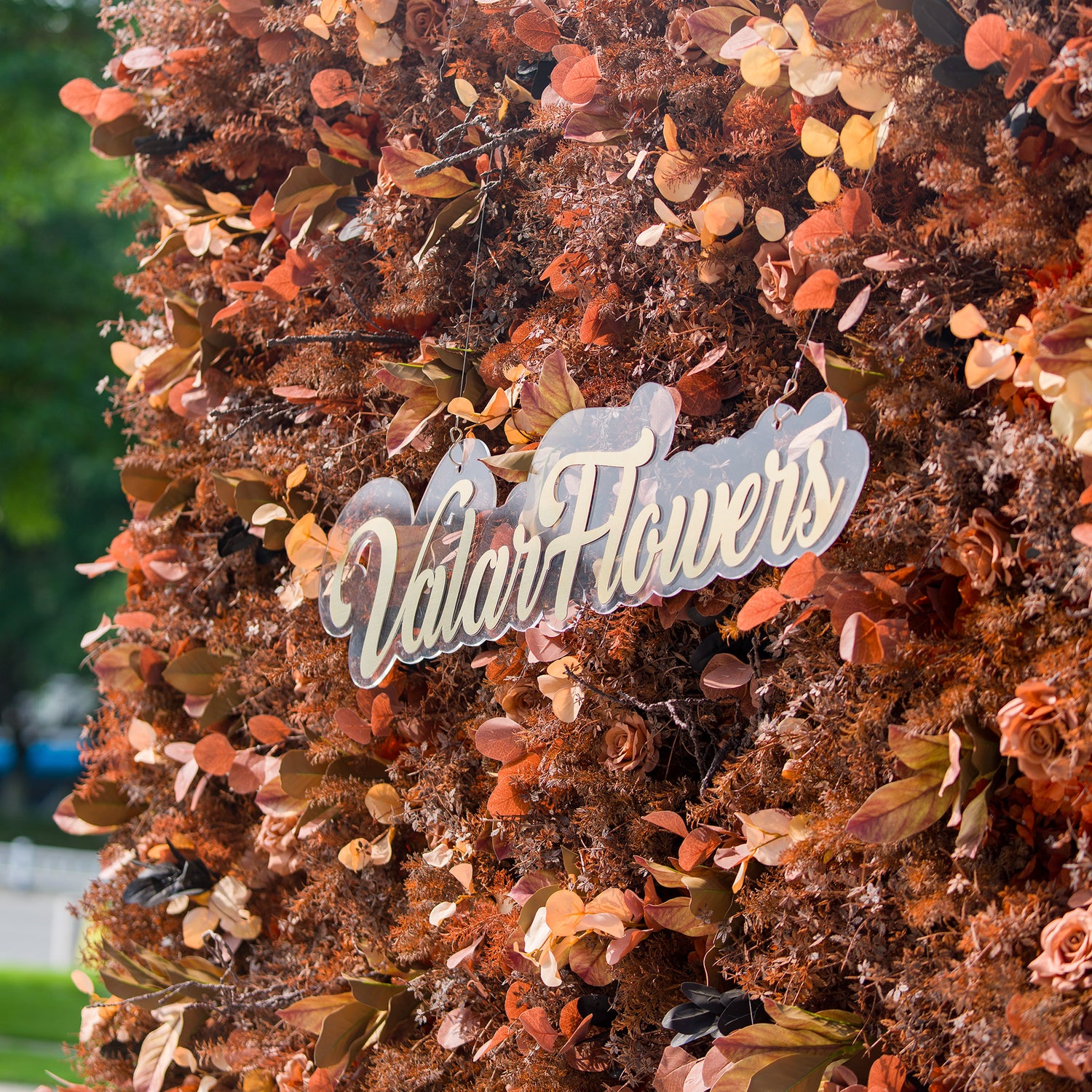 This photo showcases a rich, textured floral backdrop composed of autumn - hued flowers and foliage in shades of rust, brown, and copper. The sign “ValarFlowers” is prominently displayed. Ideal for events like an “Autumn Bounty” wedding or a fall - themed corporate event, it exudes warm, rustic charm perfect for seasonal celebrations.