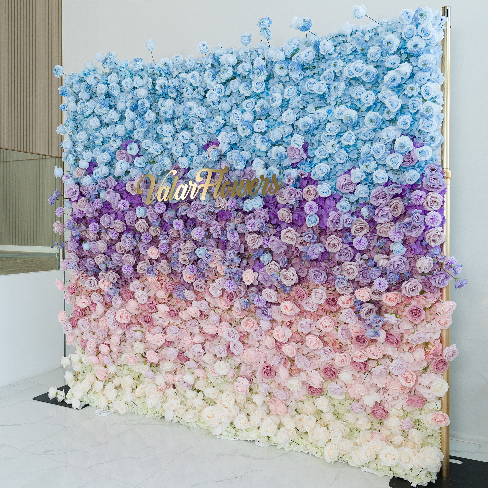 This elaborate floral wall showcases a gradient of roses and hydrangeas in hues of blue, purple, pink, and white. The ombre color theme, transitioning smoothly from deep sky - blue at the top to soft white at the base, creates a dreamy, romantic vibe. A gold “ValarFlowers” sign adds elegance. Perfect for weddings, galas, or brand events, it serves as a sophisticated, photo - worthy backdrop, blending natural beauty with polished design to elevate any occasion.