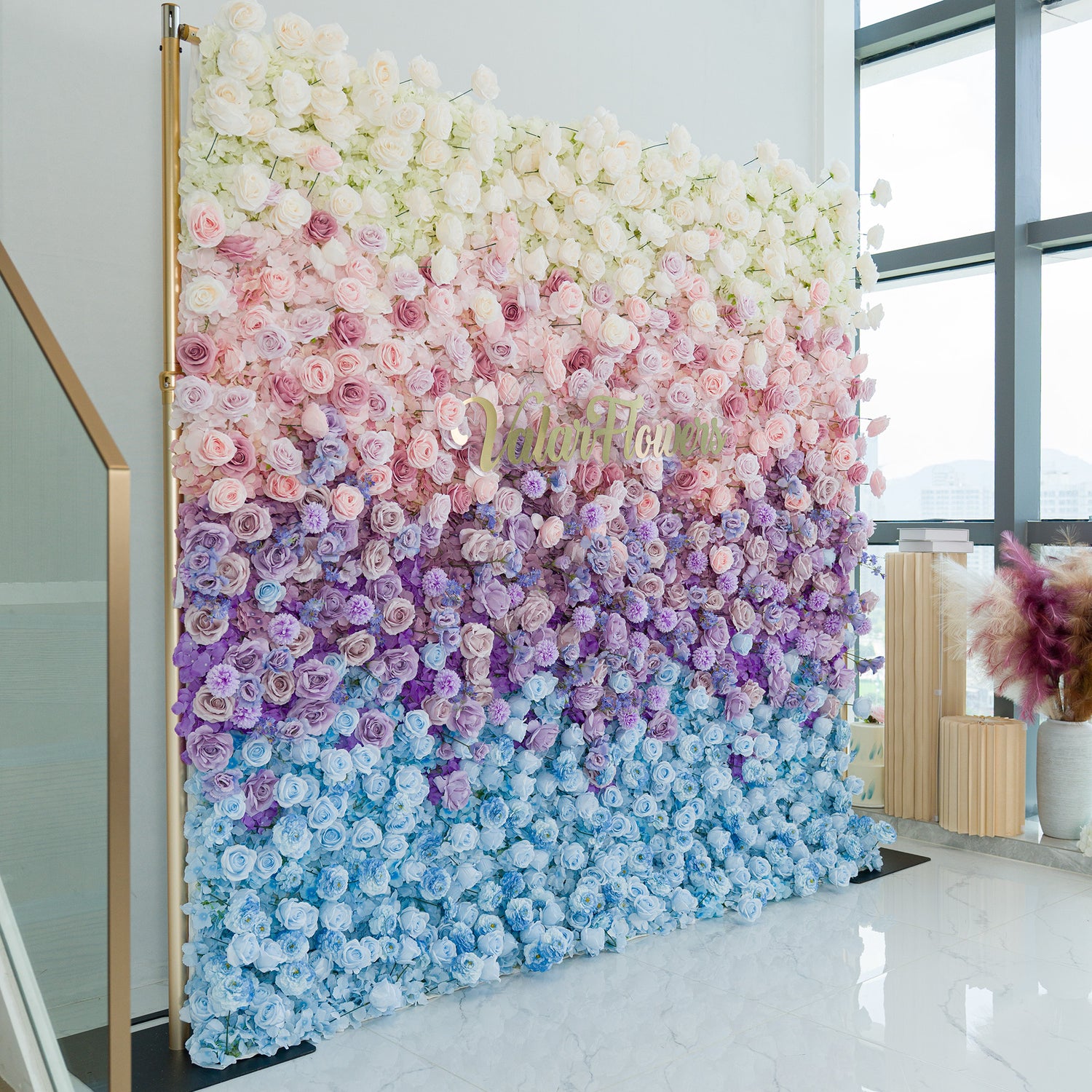 A captivating floral wall by ValarFlowers showcases a gradient of blooms—white roses, pink peonies, purple hydrangeas, and blue blossoms. The color theme transitions from soft pastels to deeper hues, creating a dreamy, elegant vibe. Set against a minimalist backdrop, it’s perfect for weddings, events, or photo backdrops, blending romance and sophistication in a lush, eye - catching display.
