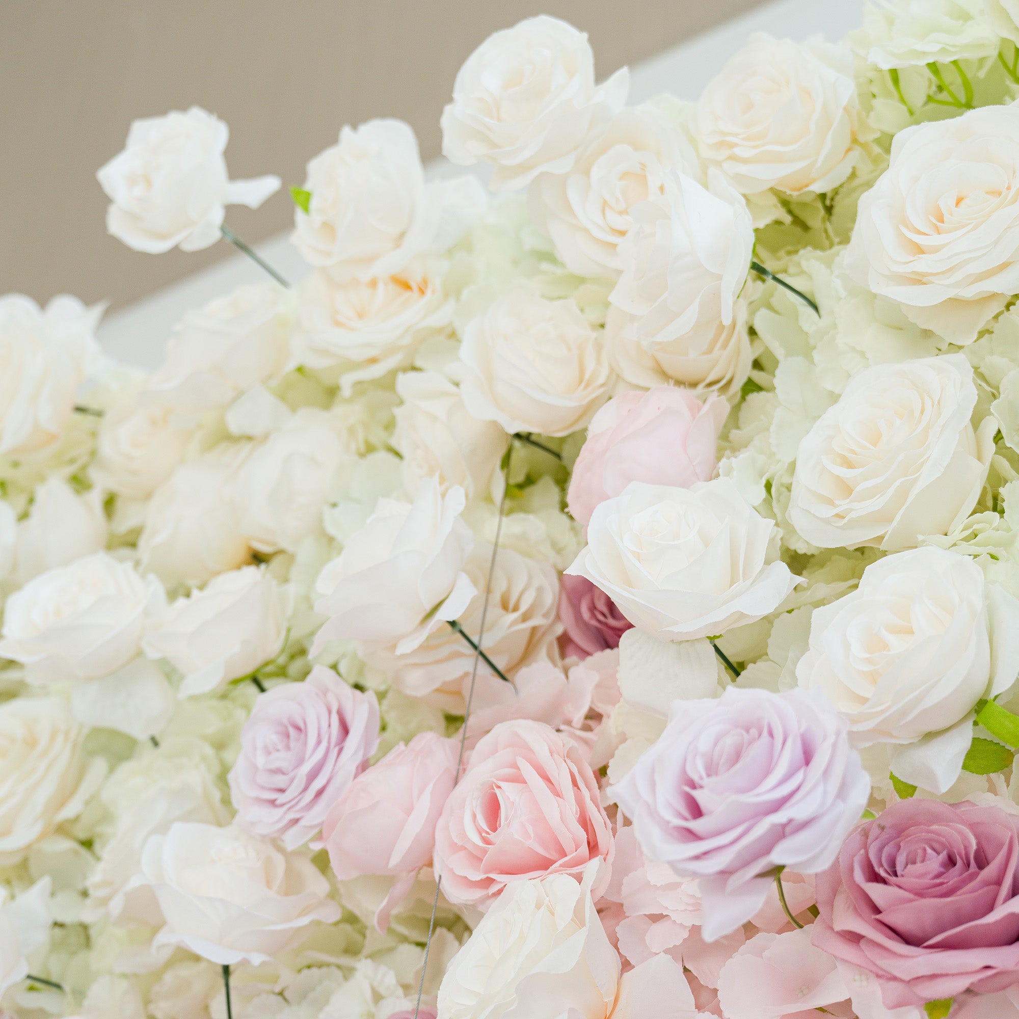 A lush arrangement of white roses, interspersed with soft pink and lavender blooms. The pastel color theme creates a romantic, elegant vibe—perfect for weddings, bridal events, or sophisticated celebrations. The dense, layered flowers offer a dreamy, polished aesthetic, ideal as a decorative backdrop or centerpiece.