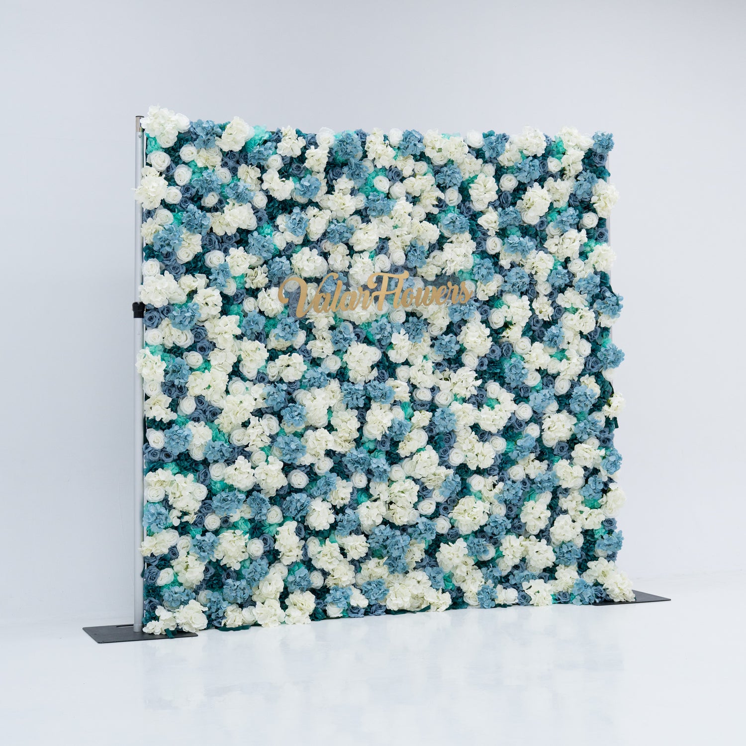 This photo shows a beautiful Valar Flowers backdrop with dense white and blue artificial roses on a plain white background. The gold "Valar Flowers" lettering adds sophistication, making it ideal for weddings and photoshoots. The meticulous arrangement enhances its aesthetic, perfect for blue-and-white themed events.