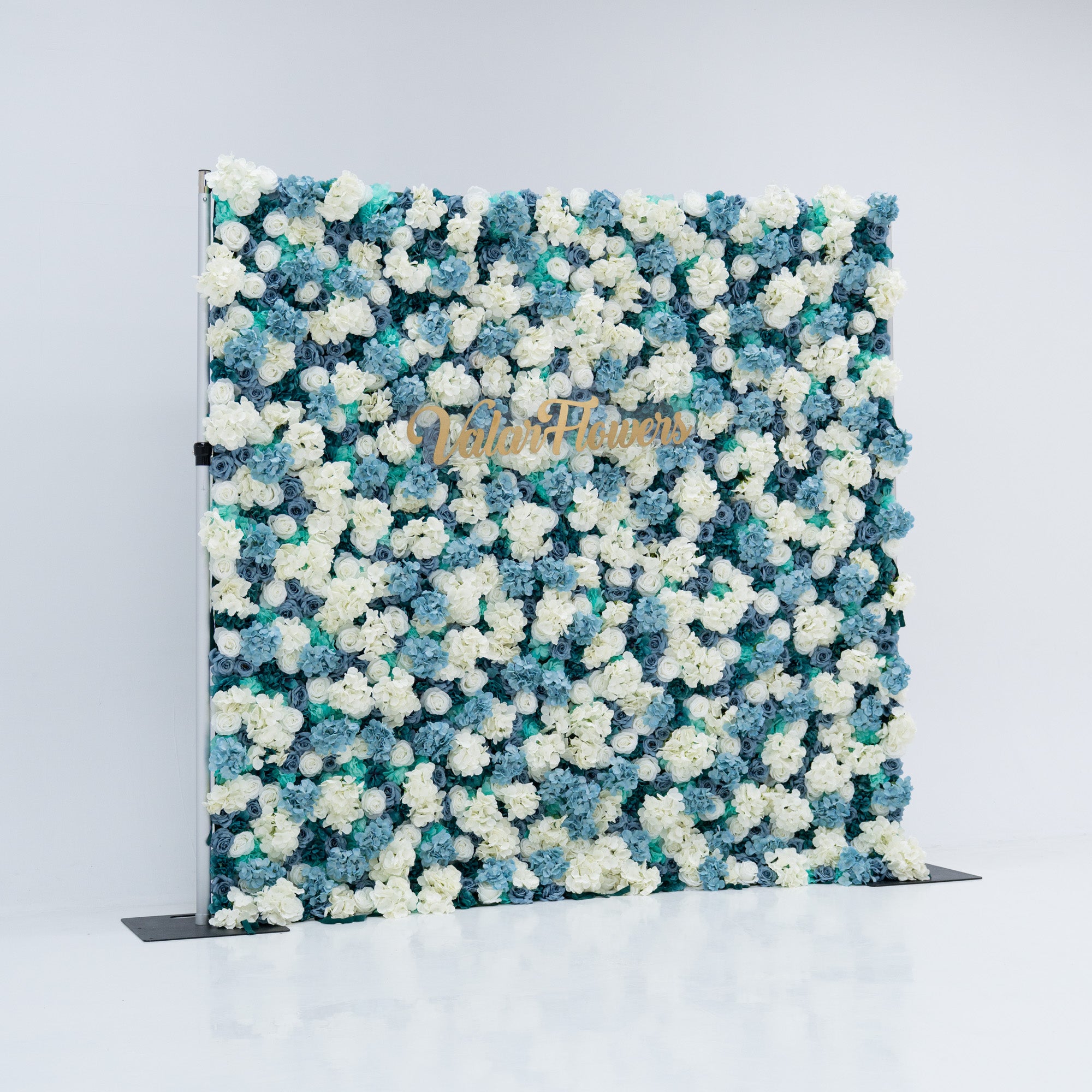 This photo shows a beautiful Valar Flowers backdrop with dense white and blue artificial roses on a plain white background. The gold "Valar Flowers" lettering adds sophistication, making it ideal for weddings and photoshoots. The meticulous arrangement enhances its aesthetic, perfect for blue-and-white themed events.