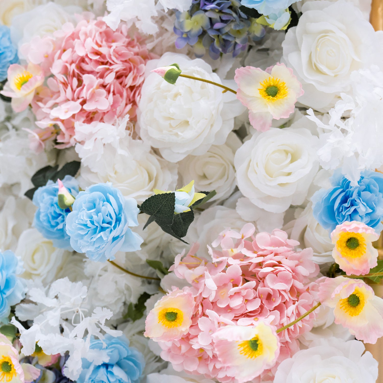This photo presents a dense arrangement of artificial flowers, with white and blue roses, and pink and blue hydrangeas. It&