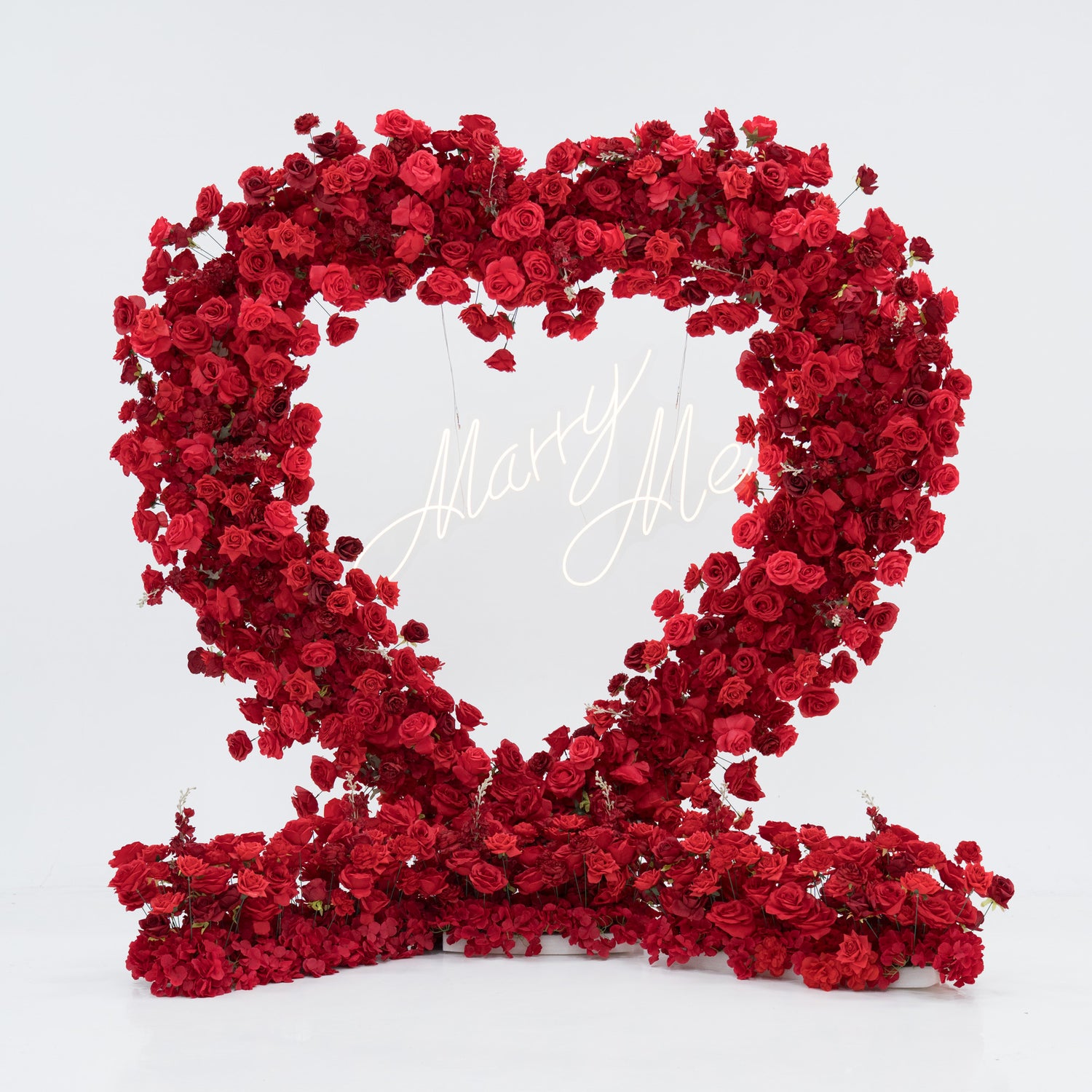 A heart - shaped floral installation crafted from abundant red roses. At its center, a glowing “Marry Me” sign adds romance. The dense, vibrant blooms form a striking, love - themed display, perfect for proposals or romantic events, blending beauty and sentiment.