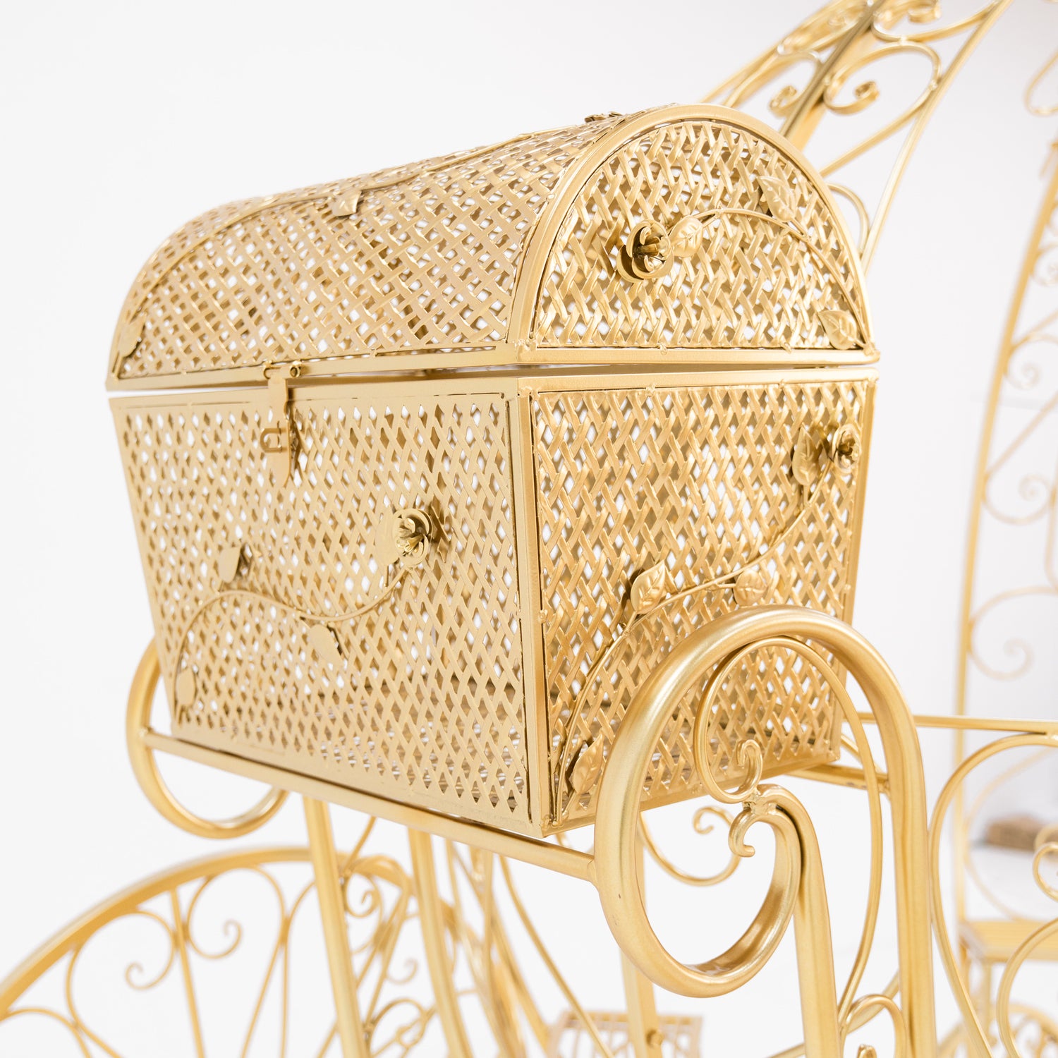 A close - up of a gold - toned, ornate metal trunk. Part of a Disney - style Cinderella carriage, it features intricate latticework, decorative floral motifs, and small clasps. The shimmering gold finish and detailed design add a fairy - tale charm, perfect for themed displays.