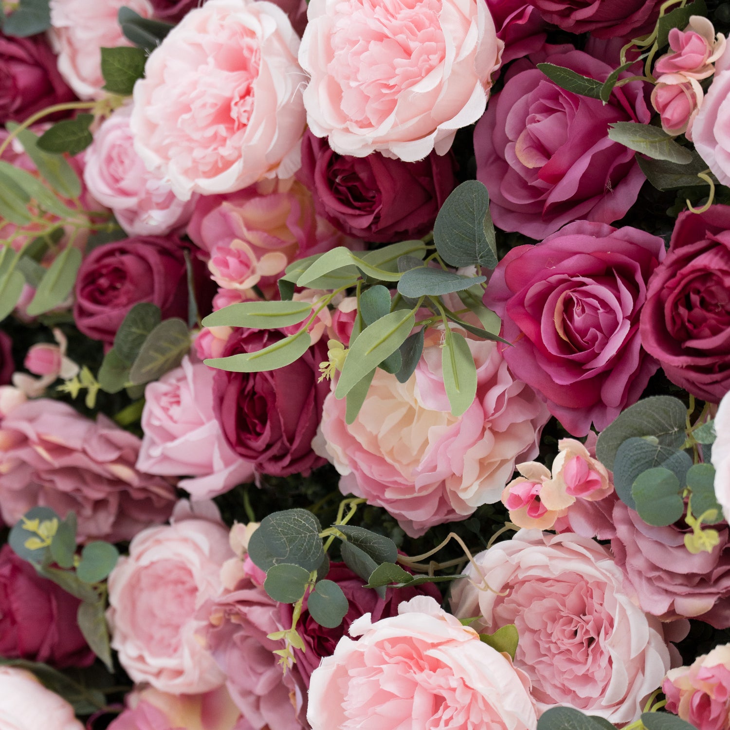 A close - up of an artificial flower wall showcases soft pink peonies, deep - pink roses, and delicate buds, all interspersed with green foliage. The lush, layered petals and varied hues create a romantic, elegant arrangement—perfect for decorative displays, adding a touch of charm and sophistication.