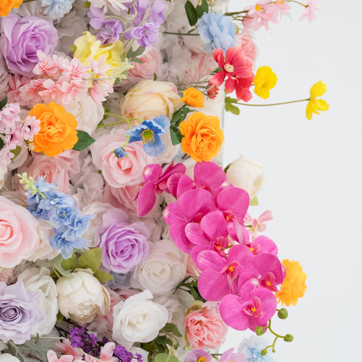 A vibrant arrangement of artificial flowers bursts with colors—pink, orange, yellow, blue, purple, and more. Various floral types, with layered petals and delicate details, create a lush, cheerful display. Set against a plain light - colored background, the dense, diverse blooms exude a festive and elegant vibe, perfect for decorative backdrops at events like weddings or parties.