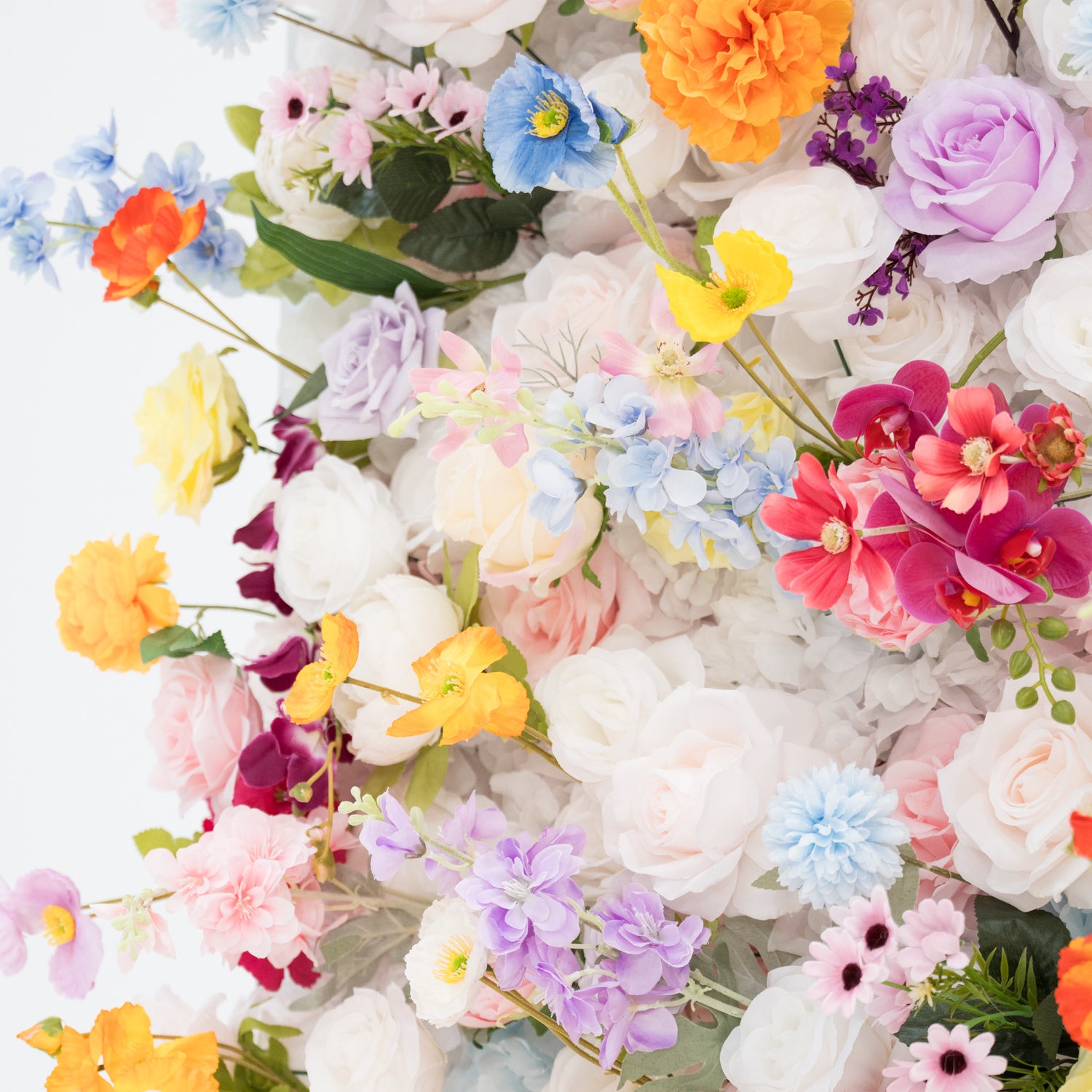A vibrant arrangement of artificial flowers showcases a rich palette of colors—pink, orange, yellow, blue, purple, and more. Various floral types, with layered petals and delicate details, create a lush, cheerful display. Set against a plain light - colored background, the dense, diverse blooms exude a festive and elegant vibe, perfect for decorative backdrops at events like weddings or parties.