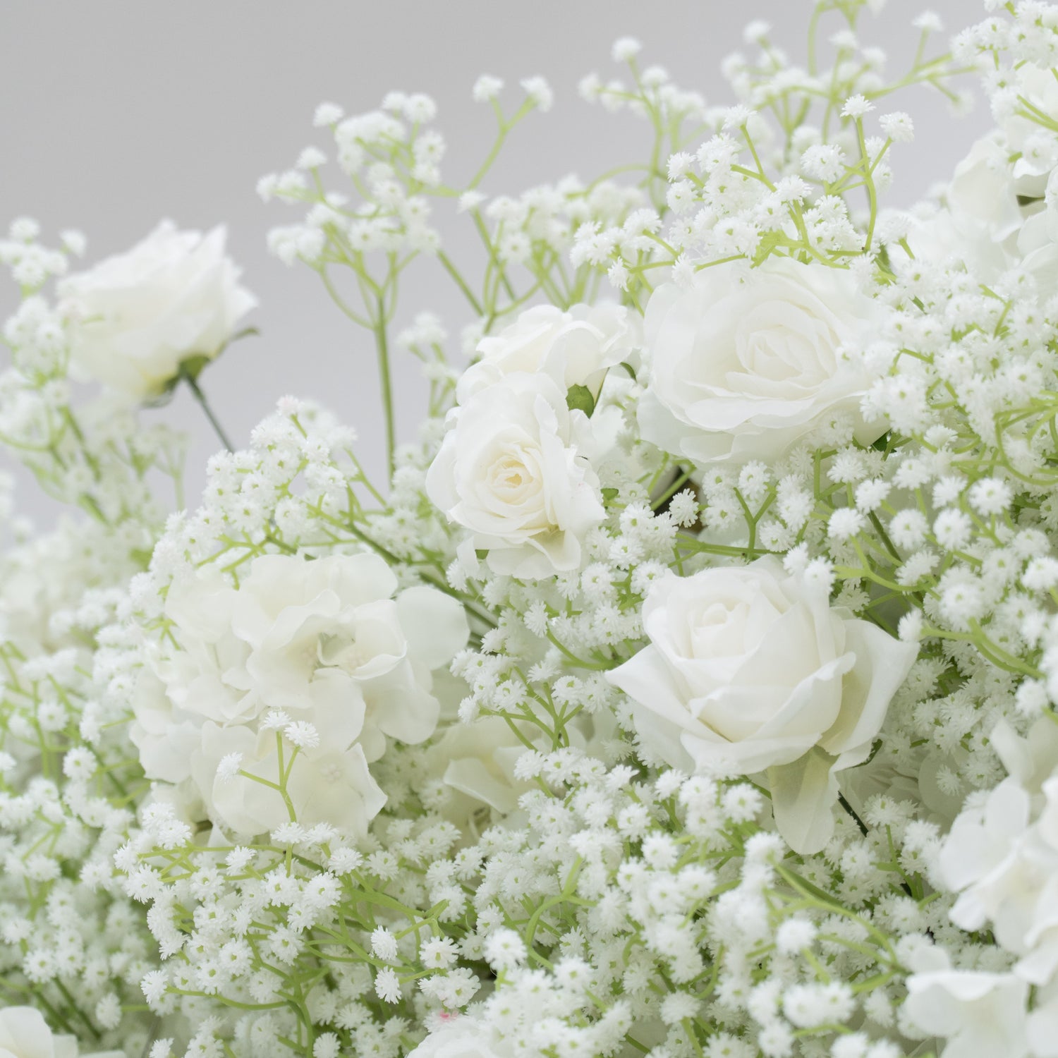 This image showcases a lush arrangement of white flowers, including roses, hydrangeas, and baby&
