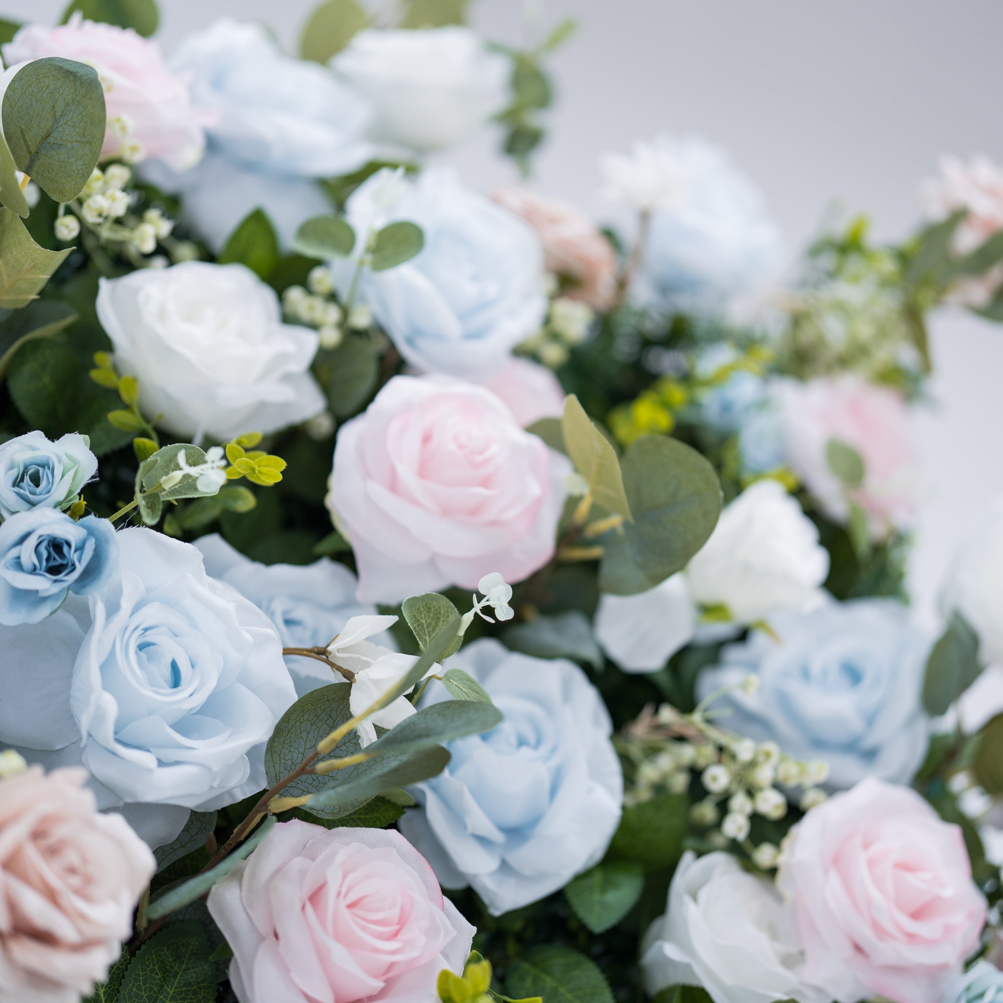 This image showcases a vibrant section of a floral backdrop by Valar Flowers, featuring a dense arrangement of artificial flowers in shades of light blue, pink, and white. Complemented by green foliage like eucalyptus, it exudes elegance and is perfect for adding a sophisticated, nature-inspired element to events, highlighting Valar Flowers’ craftsmanship in detailed, eye-catching decor.
