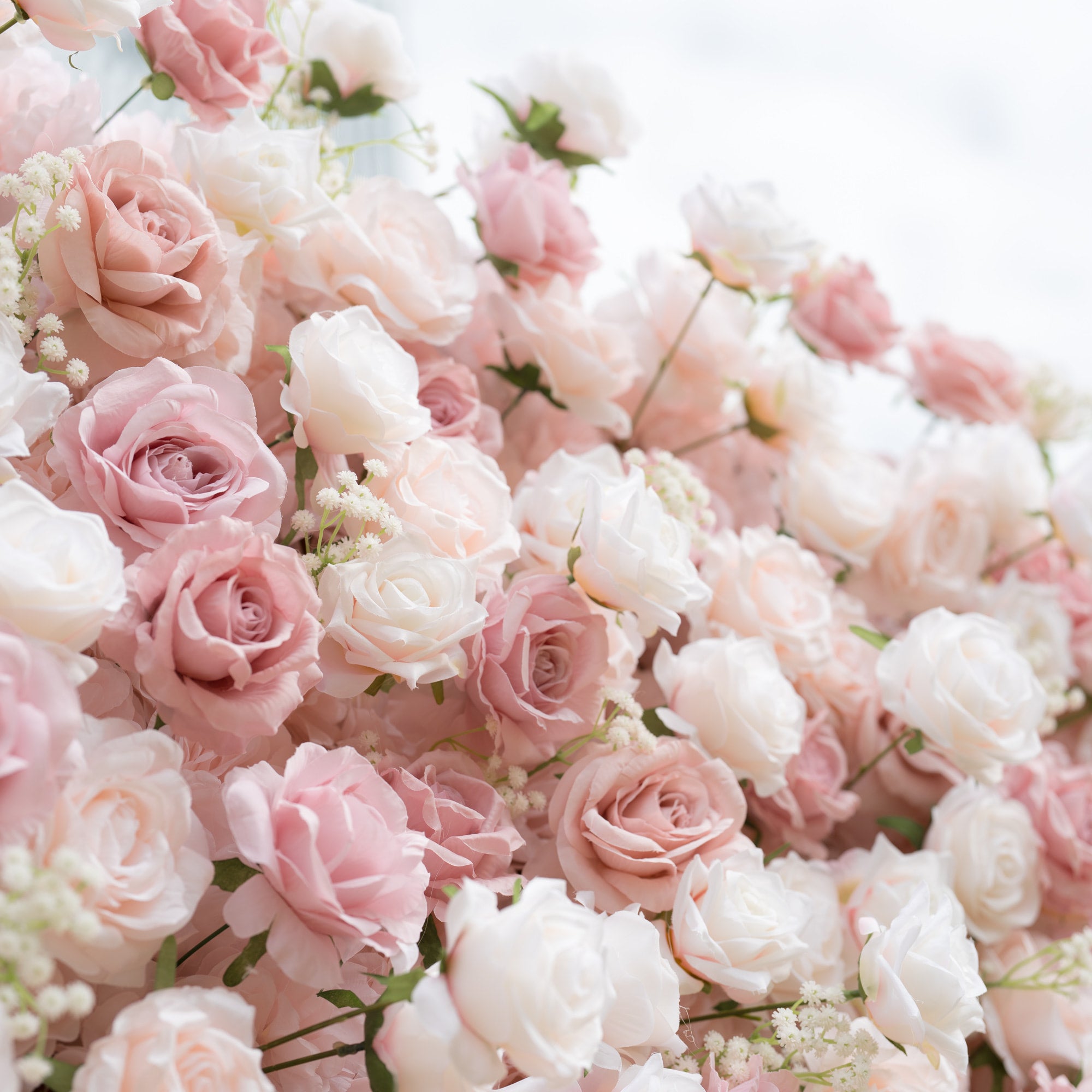 A close-up of a Valar Flowers floral arrangement, showcasing a lush, romantic blend of creamy white, soft blush, and dusty pink roses, interspersed with delicate baby&