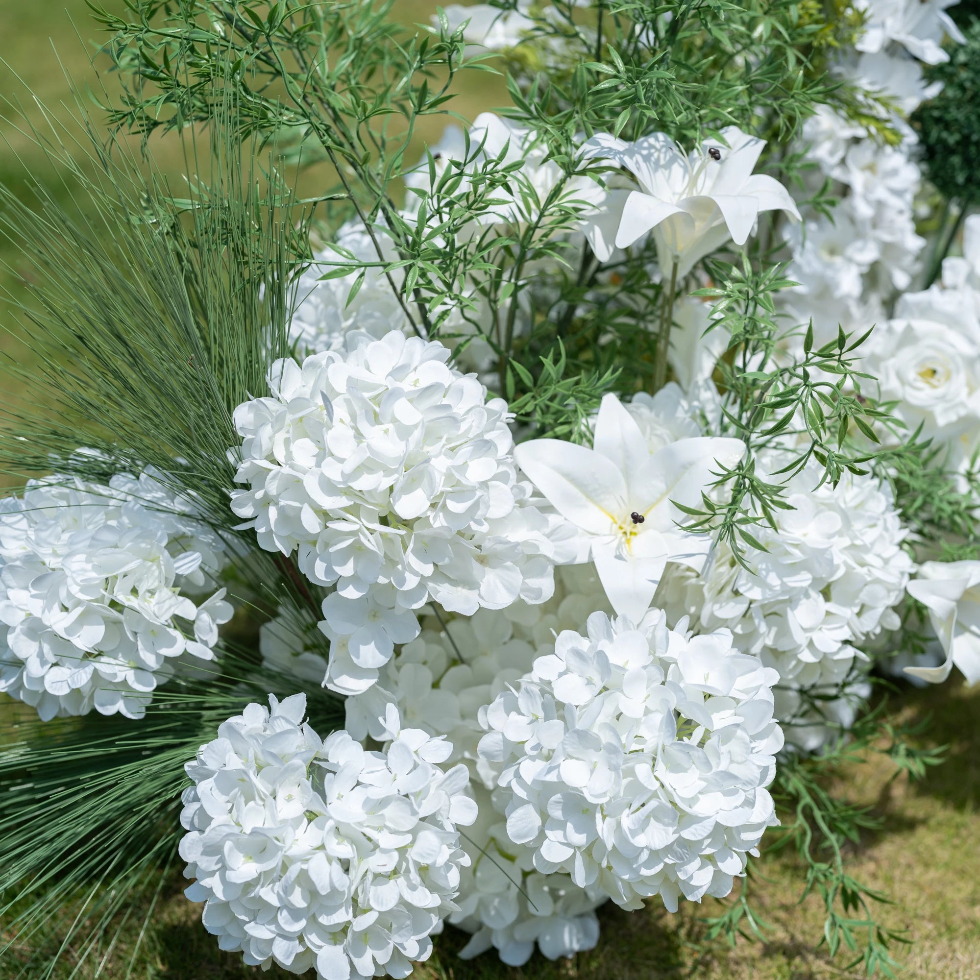 This close-up showcases Valar Flowers’ premium artificial floral arrangement, featuring lush white hydrangeas, delicate lilies, and feathery green foliage. The dense, realistic blooms mimic fresh flowers, with soft petals and lifelike textures creating an elegant, romantic aesthetic. Maintenance-free and durable, this display is ideal for weddings, photo booths, and luxury events, offering a clean, timeless look perfect for professional styling.