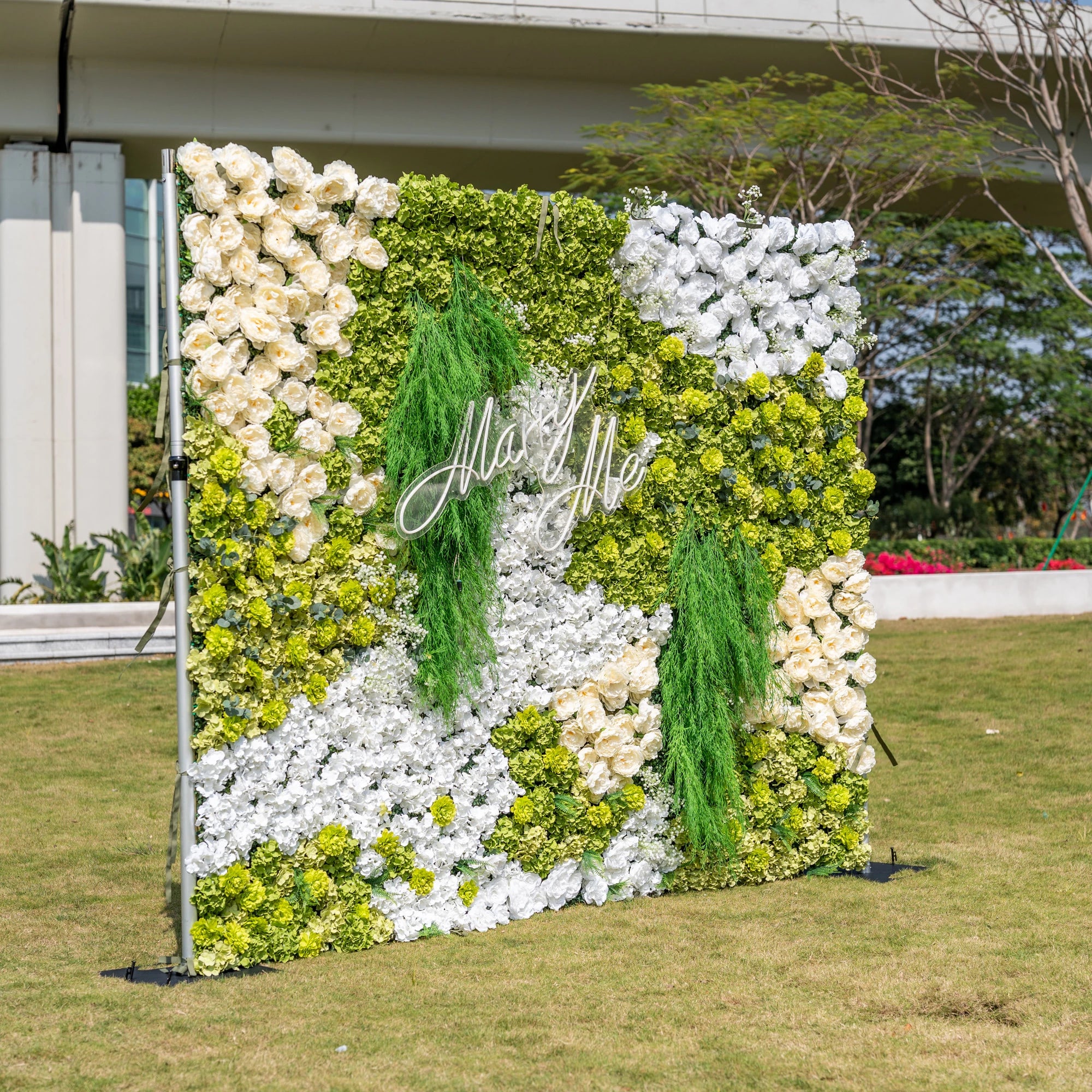 This is a stunning 10x8ft artificial flower wall backdrop by Valar Flowers, featuring a lush, nature-inspired design with vibrant green hydrangeas, cascading foliage, soft ivory roses, and crisp white blooms. Centered with a custom "Marry Me" neon sign, this reusable, maintenance-free display creates a romantic focal point, ideal for outdoor weddings, proposals, photo booths, and luxury events, offering long-lasting beauty for professional decor.