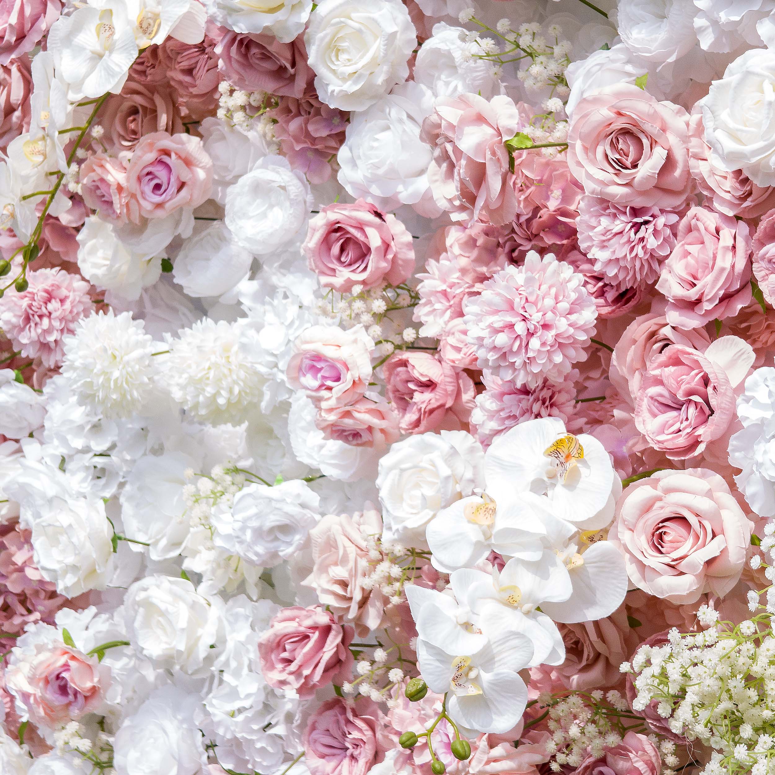 This backdrop is a lush floral arrangement with an array of artificial flowers. It prominently features white and pink roses, white orchids, and white chrysanthemums, interspersed with delicate baby&