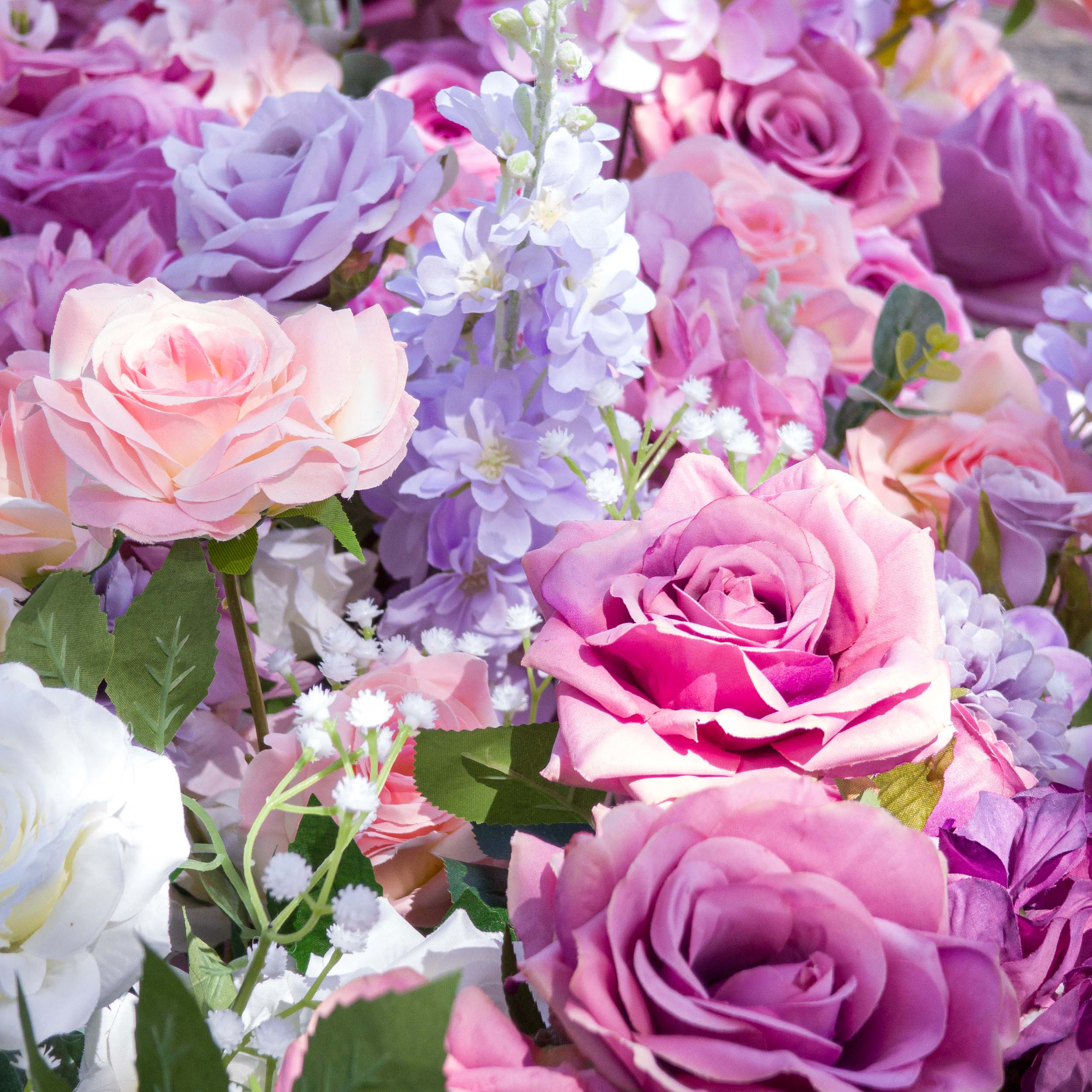 This close-up from Valar Flowers showcases a lush, romantic cluster of blooms in a soft gradient of blush pink, lavender, and deep purple—including velvety roses, delicate hydrangeas, and airy sprigs—interwoven with vibrant green foliage. The layered textures and rich hues create a dreamy, sophisticated atmosphere, ideal for weddings, engagement shoots, or elegant celebrations.