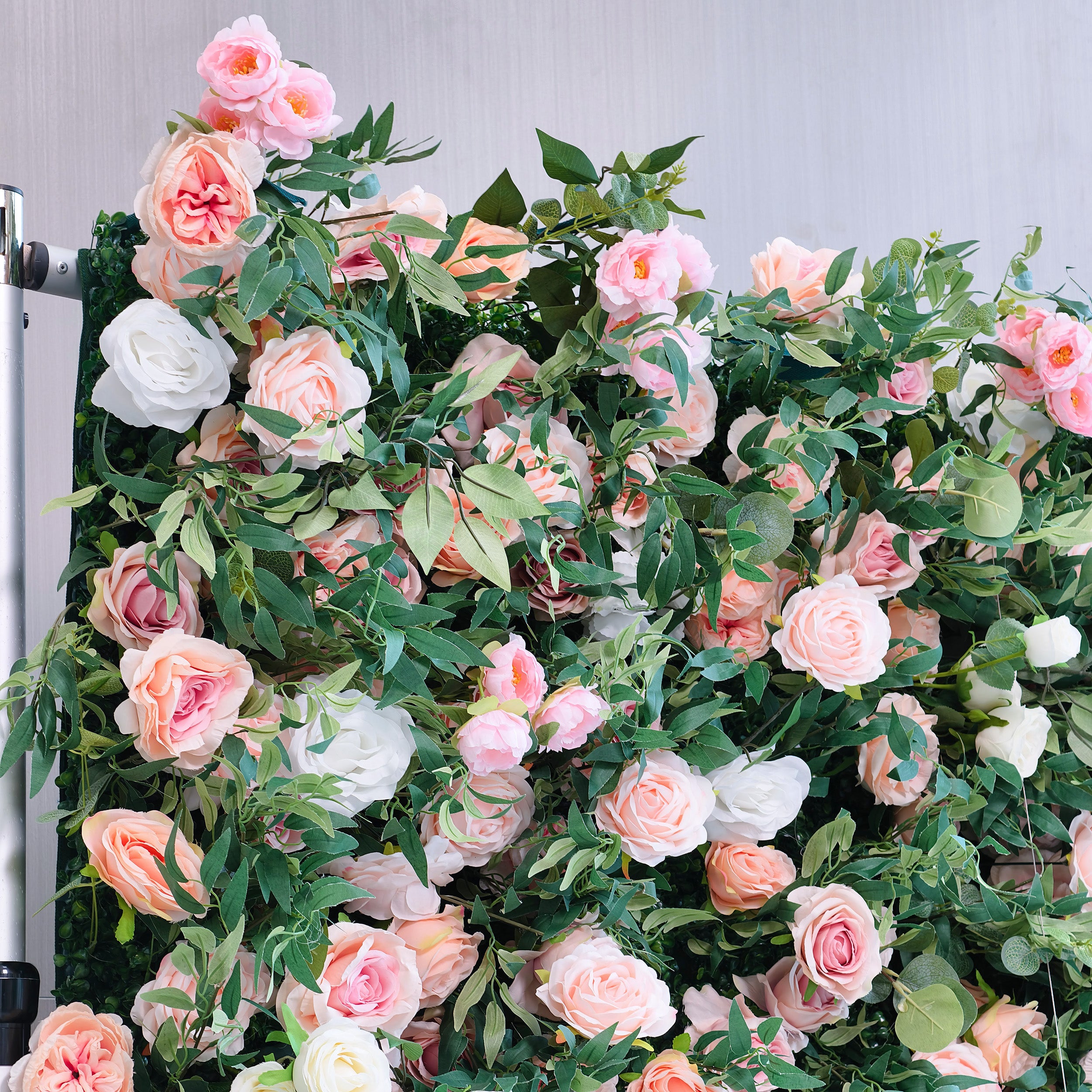 This photo showcases a lush floral arrangement with pink, peach, and white roses interspersed among green foliage. The soft, pastel colors create a romantic and elegant atmosphere. Ideal for events like bridal showers or a "Springtime Romance" garden party, it combines the beauty of roses with verdant greenery, making it a perfect decorative choice for refined and celebratory occasions.