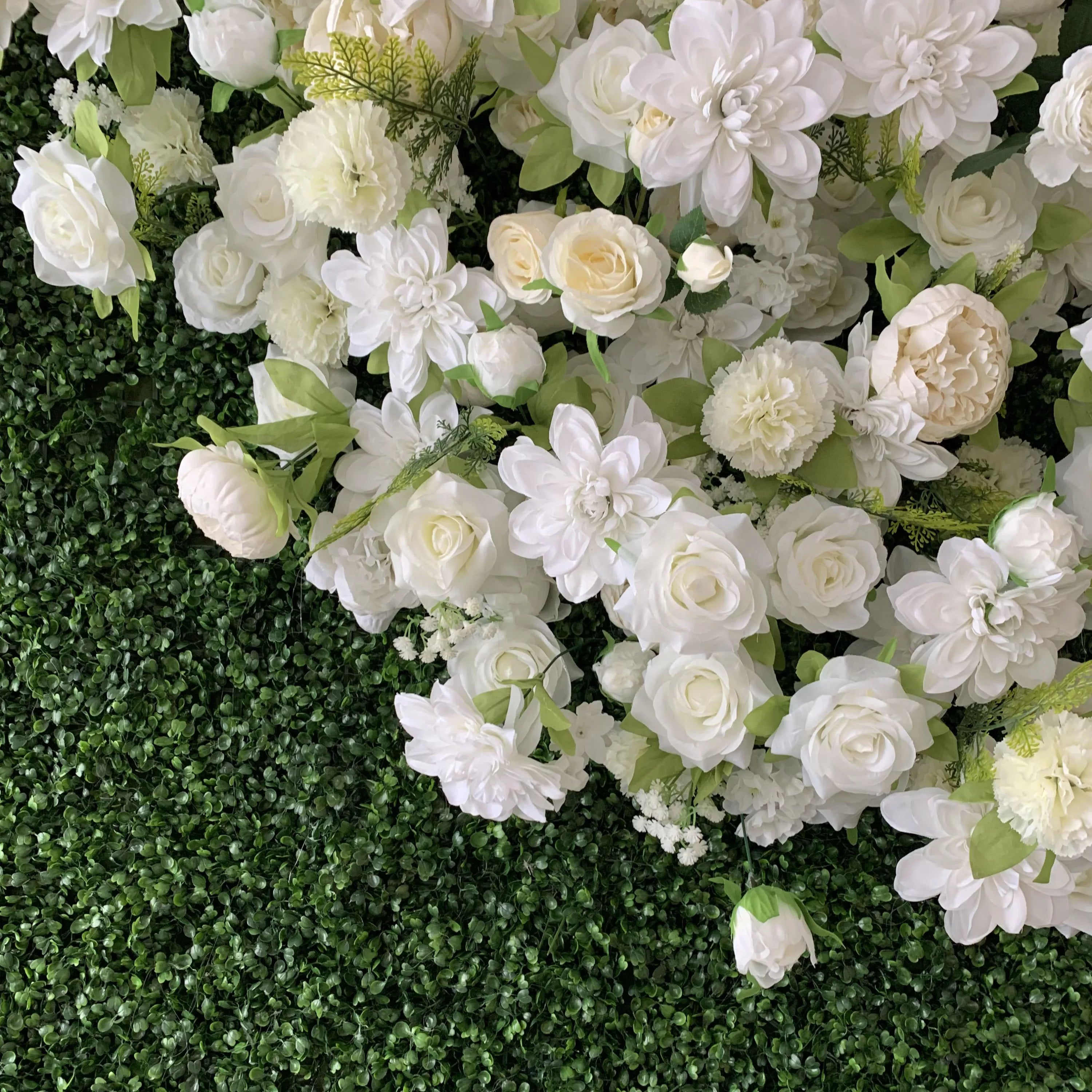 This close-up from **Valar Flowers** showcases a lush, textured floral backdrop of deep green foliage, adorned with a romantic mix of white and cream blooms—including roses, peonies, hydrangeas, and delicate baby&