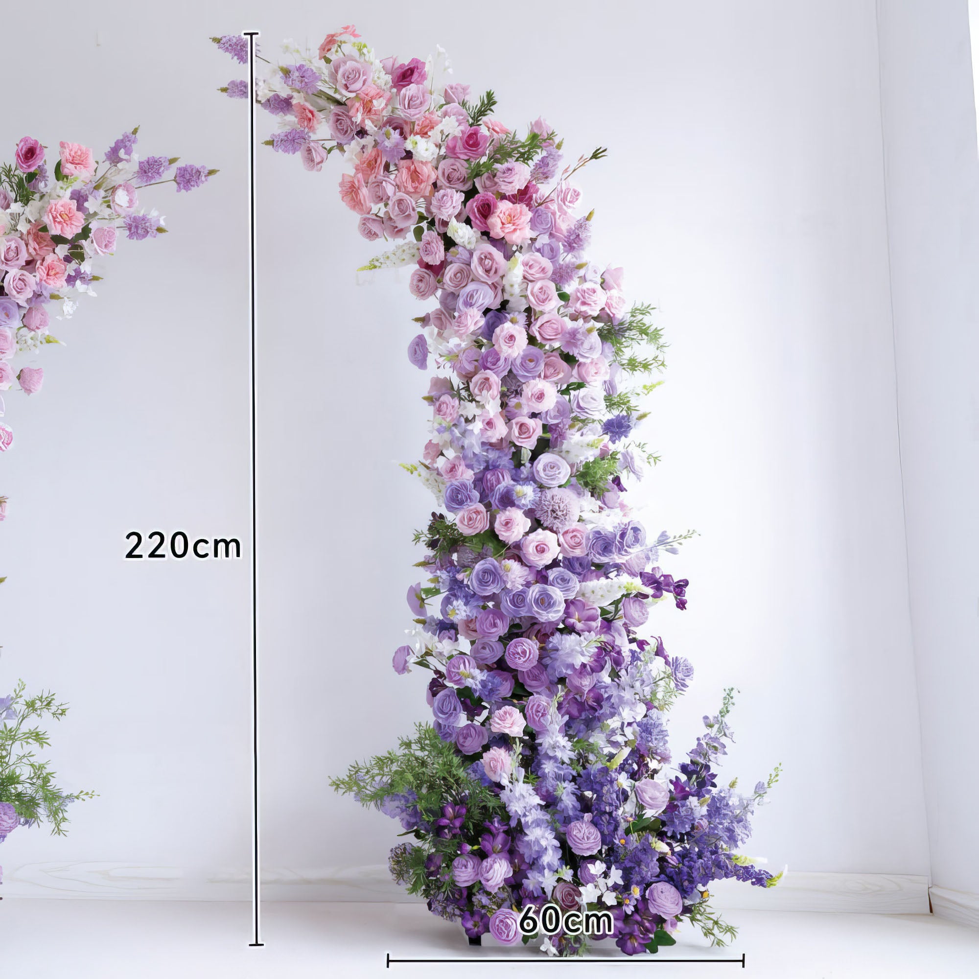 This elegant floral arch from Valar Flowers features a soft gradient of blush pink, lavender, and deep purple blooms—including roses, ranunculus, and hydrangeas—arranged in a cascading, organic shape. Standing 220cm tall and 60cm wide, it evokes a romantic, sophisticated atmosphere ideal for weddings, engagement photoshoots, or elegant celebrations.