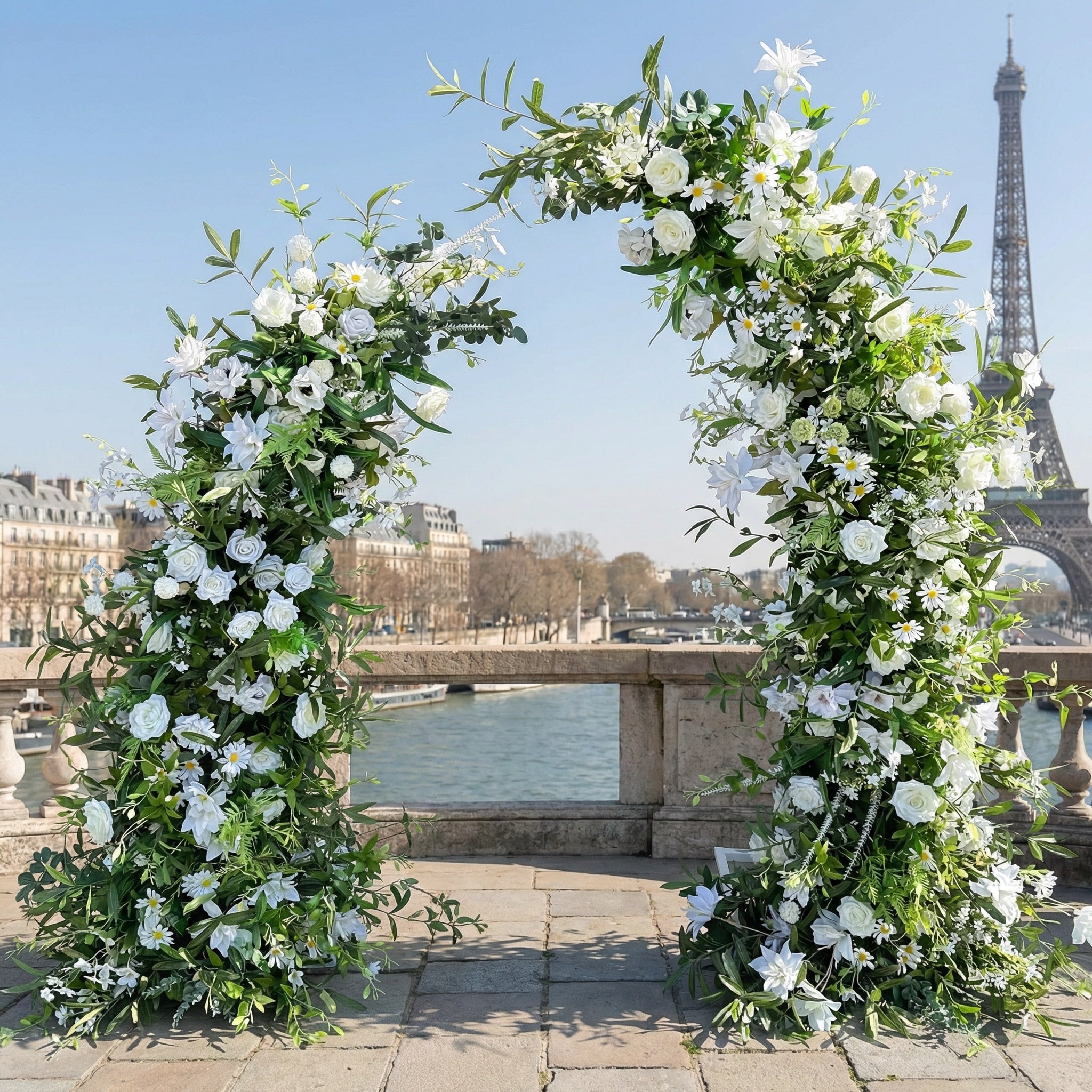 This elegant, asymmetrical floral arch from Valar Flowers is crafted with a fresh palette of crisp white blooms (roses, lilies, daisies) intertwined with lush green eucalyptus and foliage. Set on a sun-dappled Parisian terrace with the iconic Eiffel Tower in the background, it creates a romantic, airy, and sophisticated atmosphere perfect for intimate weddings and refined photoshoots.