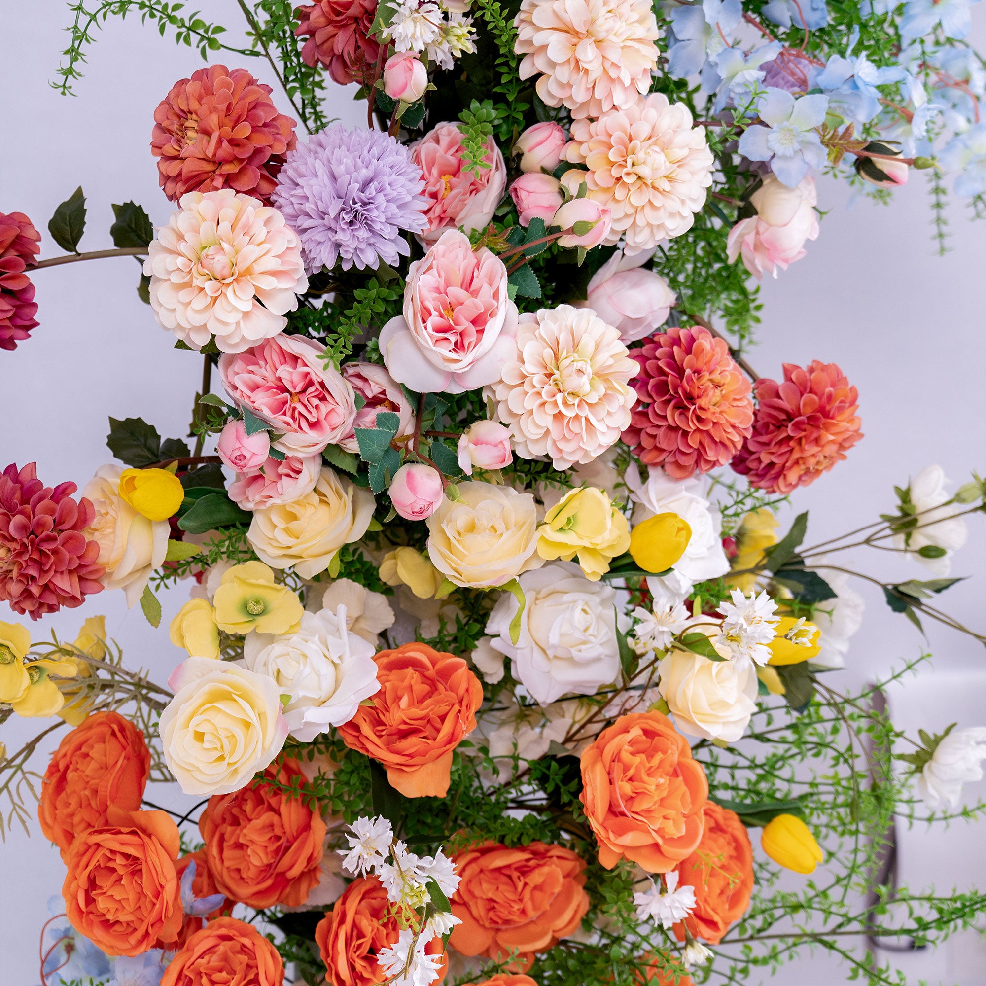 This photo showcases a vibrant, dense arrangement of artificial flowers. It includes roses, dahlias, and chrysanthemums in a spectrum of colors—soft pink, peach, lavender, cream, and bold orange. Interspersed with delicate white blooms and green foliage, the mix of hues and textures creates a lively, celebratory vibe. Perfect for weddings, events, or decor, the realistic faux flowers offer long - lasting beauty, ideal for adding a burst of color and elegance to any setting.