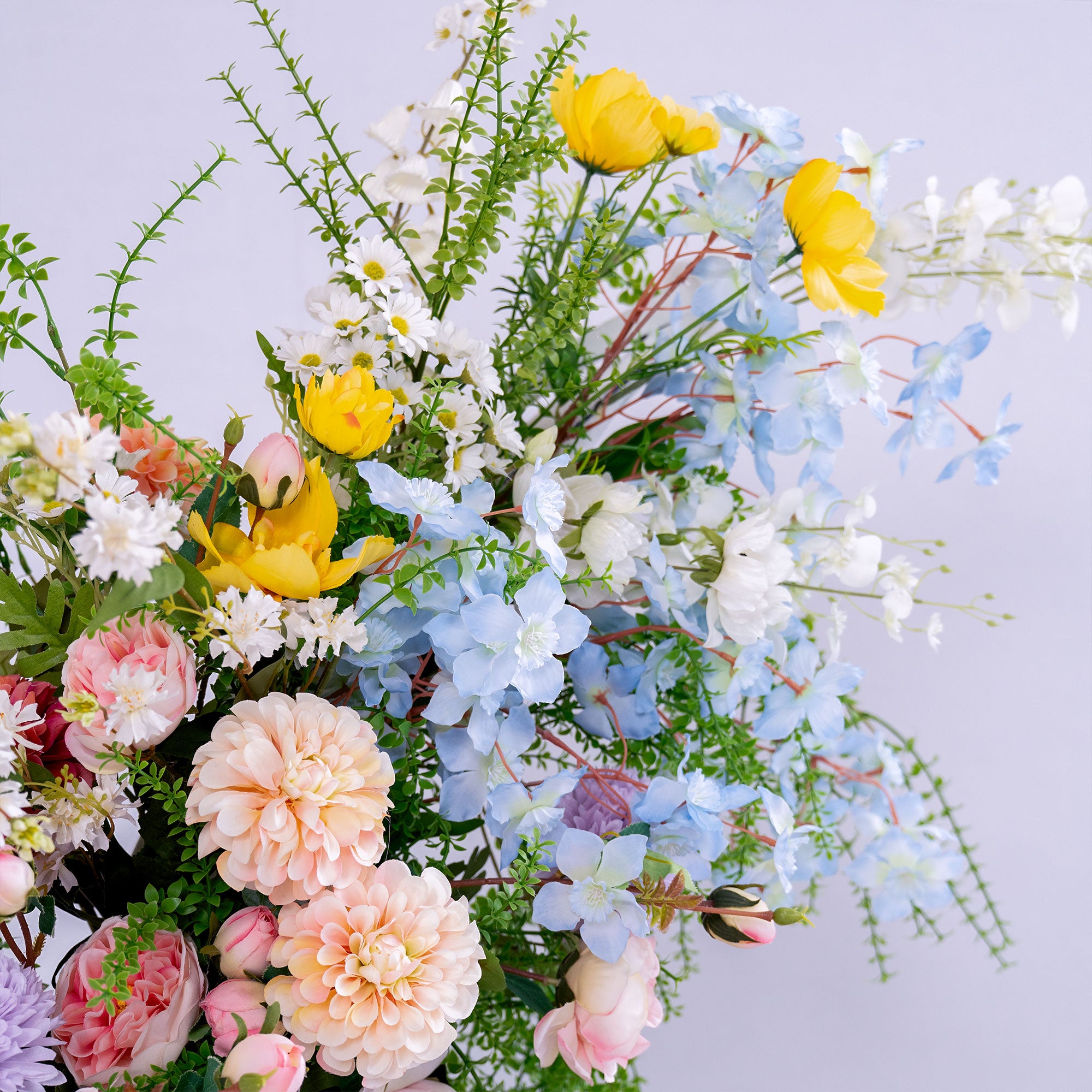 This photo presents a beautiful arrangement of artificial flowers. It includes soft pink roses, peach - toned dahlias, bright yellow blooms, delicate white daisies, and light blue blossoms, all mixed with lush green foliage. The pastel and vibrant hues create a fresh, cheerful vibe, perfect for adding a touch of natural elegance to weddings, events, or home decor. The realistic textures of the faux flowers offer long - lasting beauty, ideal for crafting a charming and polished aesthetic.