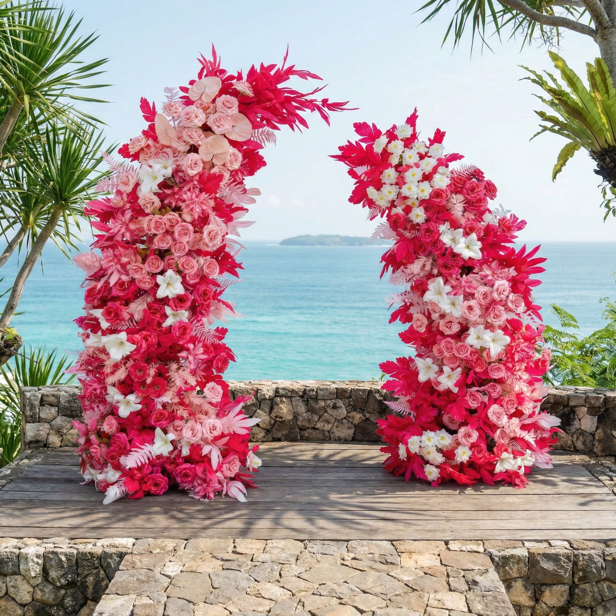 This vibrant floral arch from Valar Flowers is a lush, cascading arrangement of soft pink, deep fuchsia, and white blooms—including roses, lilies, and delicate sprigs—interwoven with bold red foliage. Set against a stunning tropical ocean backdrop, it creates a romantic, energetic atmosphere ideal for beach weddings, engagement photoshoots, or joyful celebrations.