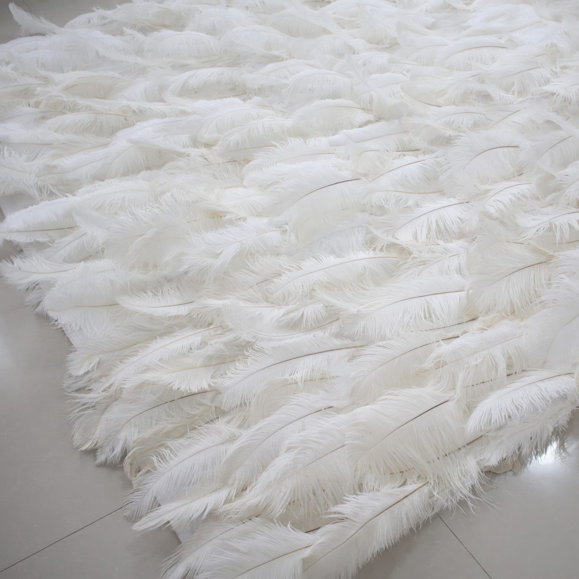 This image showcases a luxurious white feather backdrop by Valar Flowers. Densely packed with soft, pristine white feathers, it creates a plush, ethereal, and elegant display. The feathers&