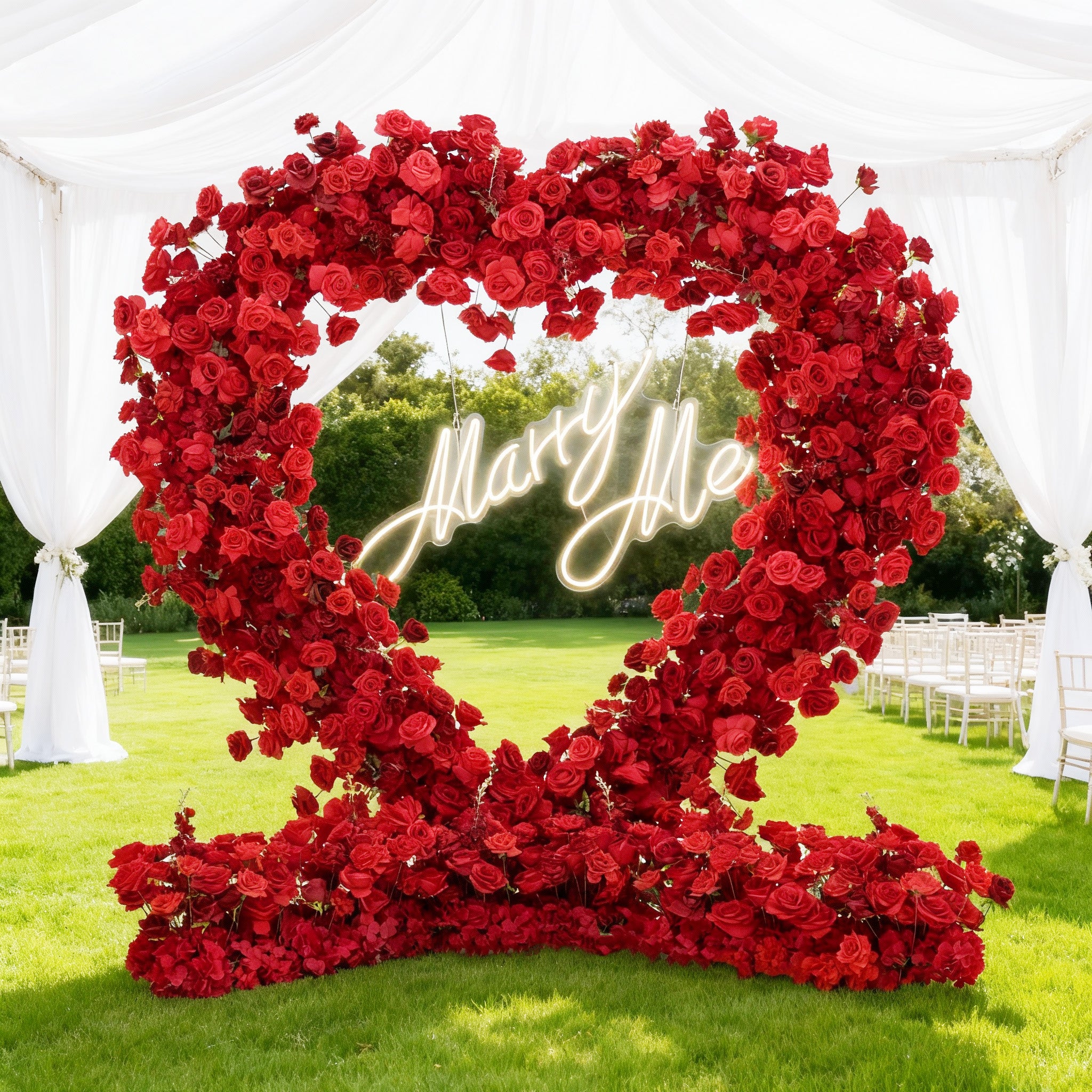 This image shows a romantic outdoor scene with a heart - shaped arch made of red roses. Inside the arch, a glowing “Marry Me” neon sign hangs. The setting is a lush green lawn under a white draped canopy, with white chairs arranged, perfect for a proposal or wedding - related event.