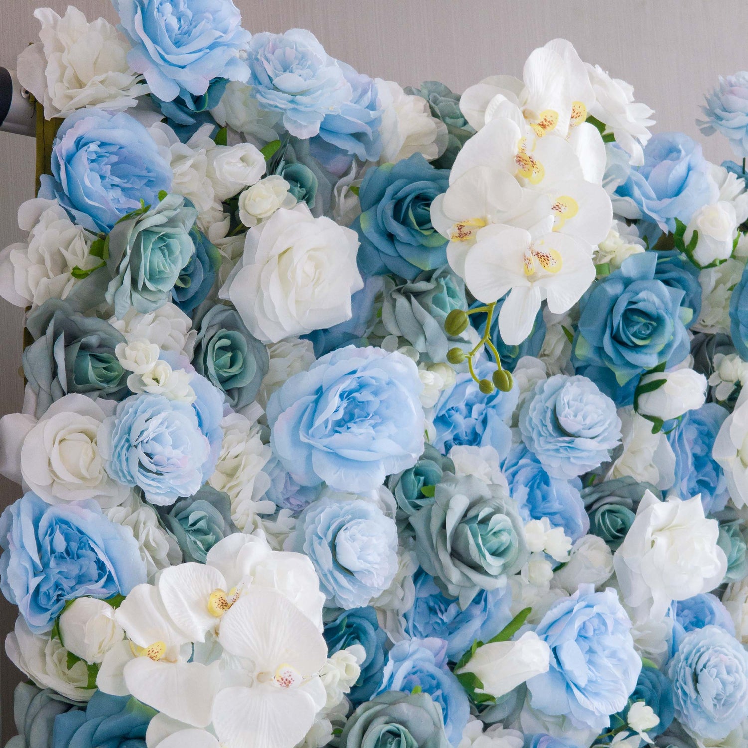 This photo showcases a lush, dense floral arrangement featuring a beautiful blend of blue and white roses, complemented by elegant white orchids. The varying shades of blue and white create a visually soothing and harmonious effect. The roses&