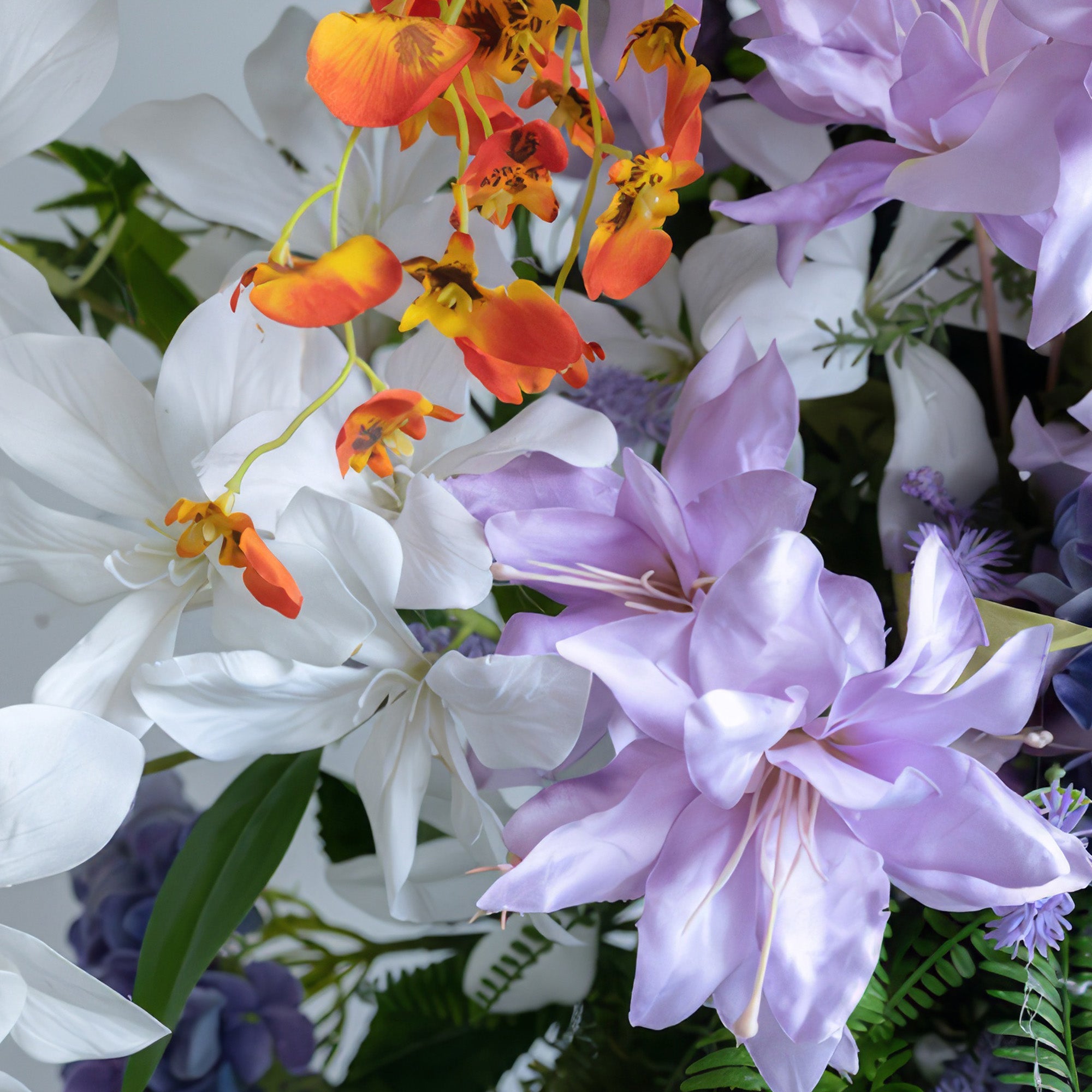 This image shows an artificial flower arrangement with a vibrant color palette of white, purple, and orange. It features large, broad - petaled white and purple flowers, along with small orange blooms, presenting a lively and exotic style. 