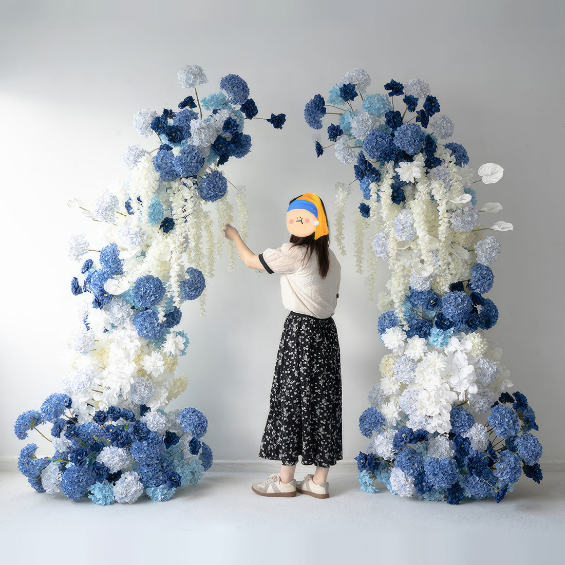 This flower arch combines various shades of blue with crisp white. Featuring hydrangeas and other blooms, it creates a cool, elegant style. Ideal for weddings, photo shoots, and events, it makes a beautiful backdrop and a great spot for memorable pictures.