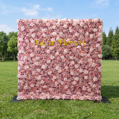 Soft multi-tone blush artificial flower wall covered in layered dusty pink, mauve, cream roses and delicate filler blooms, set on a sunlit green lawn. Elegant golden "Valar Flowers" branding sits front and center. This reusable, low-upkeep floral backdrop works for wedding photo booths, boutique brand displays, bridal events and pastel aesthetic social media content shoots, offering lush romantic texture.