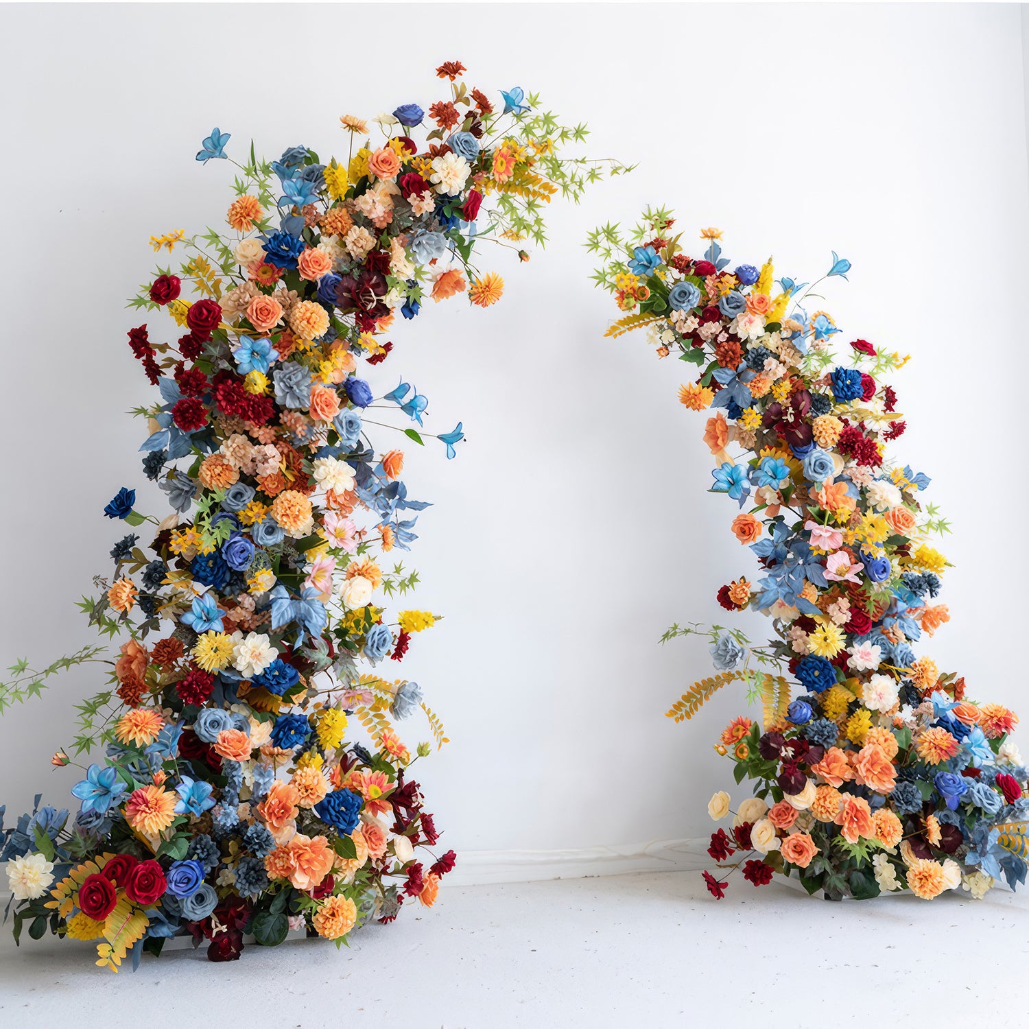 The image features a floral arch bursting with color, including vivid blues, warm oranges, deep reds, and soft pastels. It has roses, daisies, and other blooms. The style is bold, festive, and full of energy.  