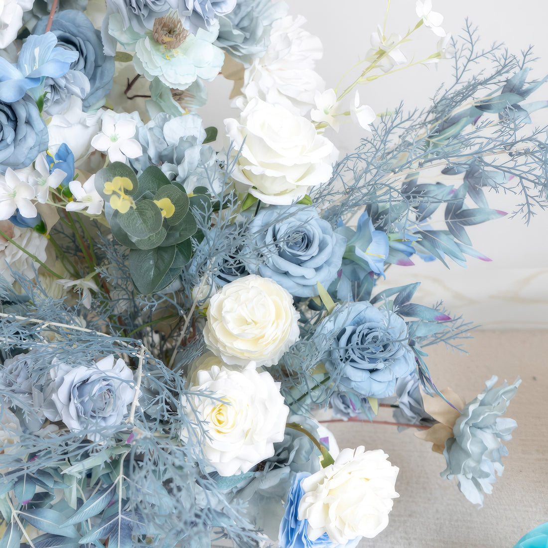 This close - up shows a harmonious blend of artificial flowers in a cool color palette. White roses stand out among various shades of blue blooms, including blue roses and light blue blossoms. The addition of blue - toned foliage gives it an elegant, calming, and sophisticated style.