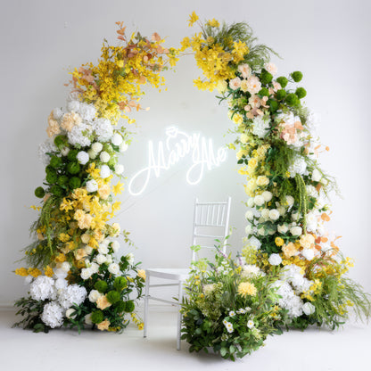 This is a romantic wedding - themed floral arch crafted from artificial flowers. It features a cheerful combination of bright yellow blooms, pure white hydrangeas, and lush green foliage. The &quot;Marry Me&quot; neon sign adds a sweet touch, creating a fresh and inviting atmosphere. 