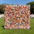 This image showcases a vibrant floral wall brimming with artificial flowers in a riot of colors, including orange, pink, blue, purple, and white. The dense arrangement features various types of blooms, creating a lively and eye - catching display. Set against an outdoor backdrop with greenery and a clear blue sky, it exudes a festive and cheerful atmosphere, perfect for events or photo backdrops. 