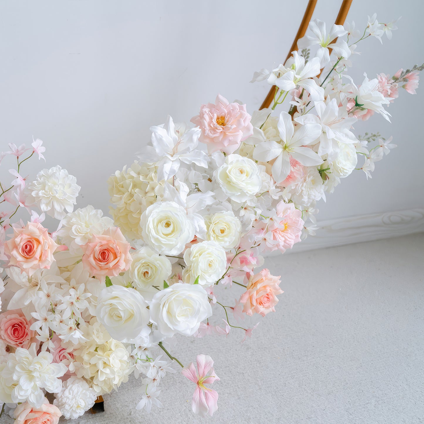 This image features an artificial flower arrangement with roses, hydrangeas, and other blooms. Colors range from white to soft pink and peach. The style is delicate and charming, perfect for a romantic or elegant setting. 