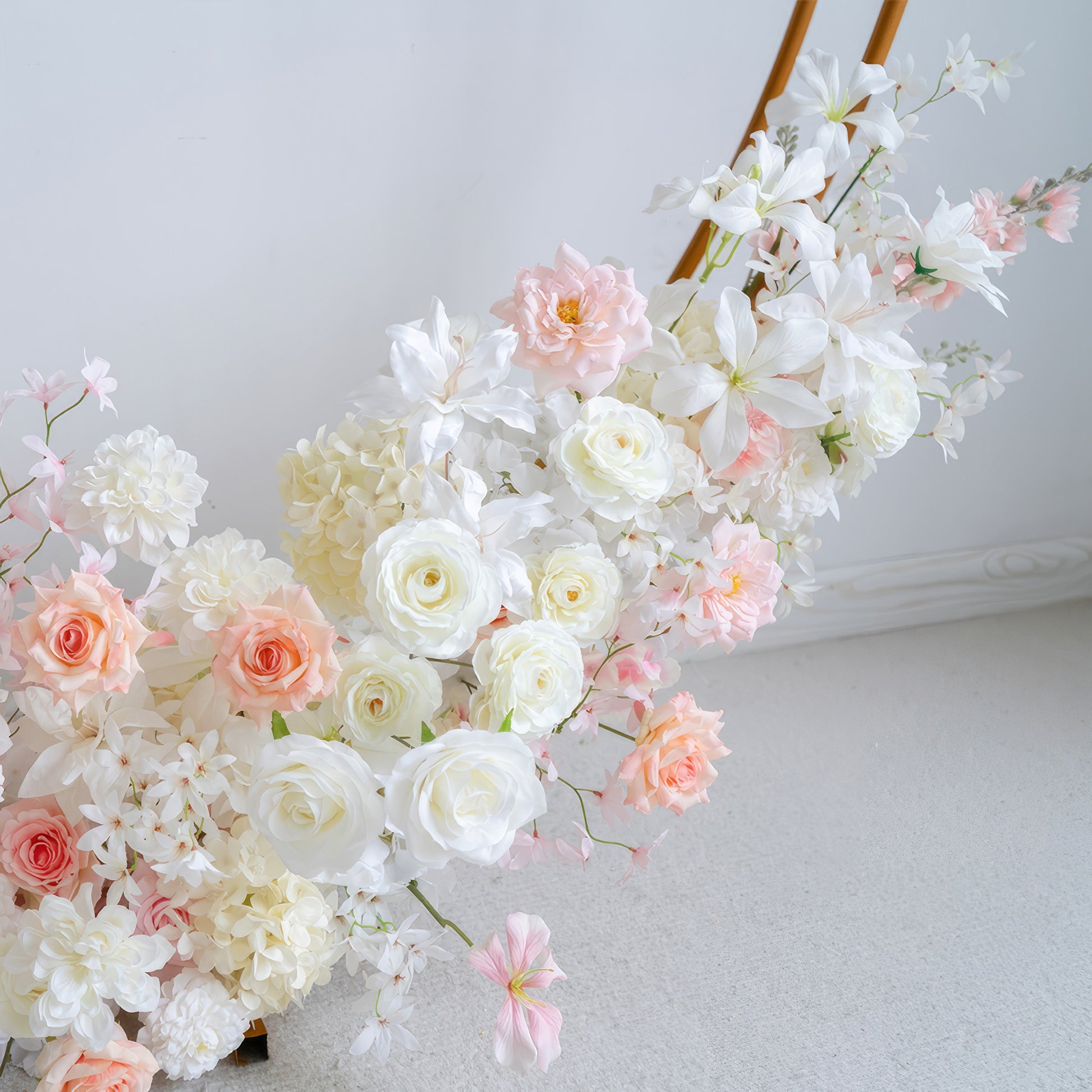 This image features an artificial flower arrangement with roses, hydrangeas, and other blooms. Colors range from white to soft pink and peach. The style is delicate and charming, perfect for a romantic or elegant setting. 