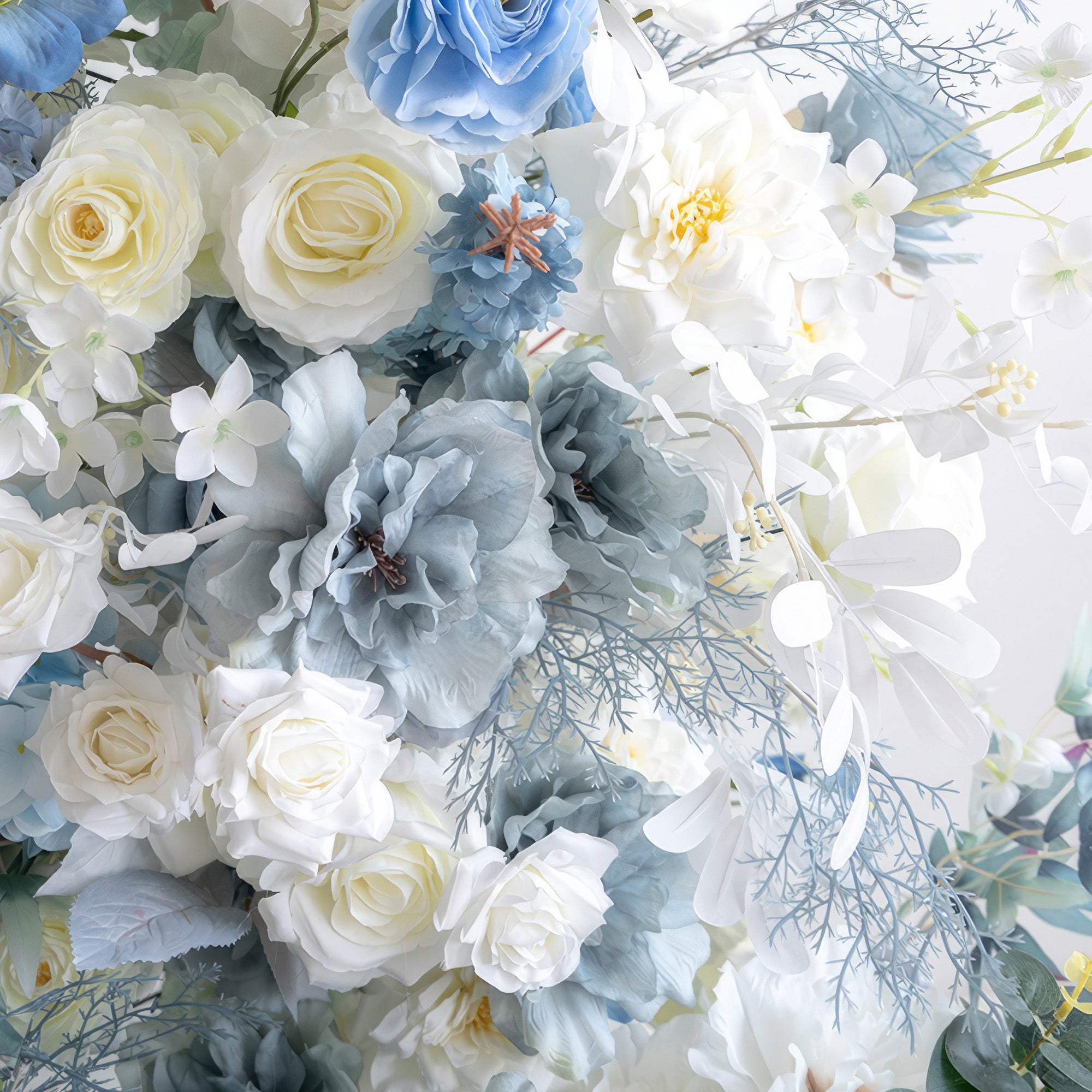 This image showcases a cluster of artificial flowers in a serene blue - and - white color scheme. White roses and various white blooms are paired with blue flowers in different shades, like blue roses and large blue - gray blossoms, along with blue - toned foliage. The arrangement exudes an elegant, tranquil, and layered style, perfect for decorating weddings, sophisticated parties, and similar events. 

