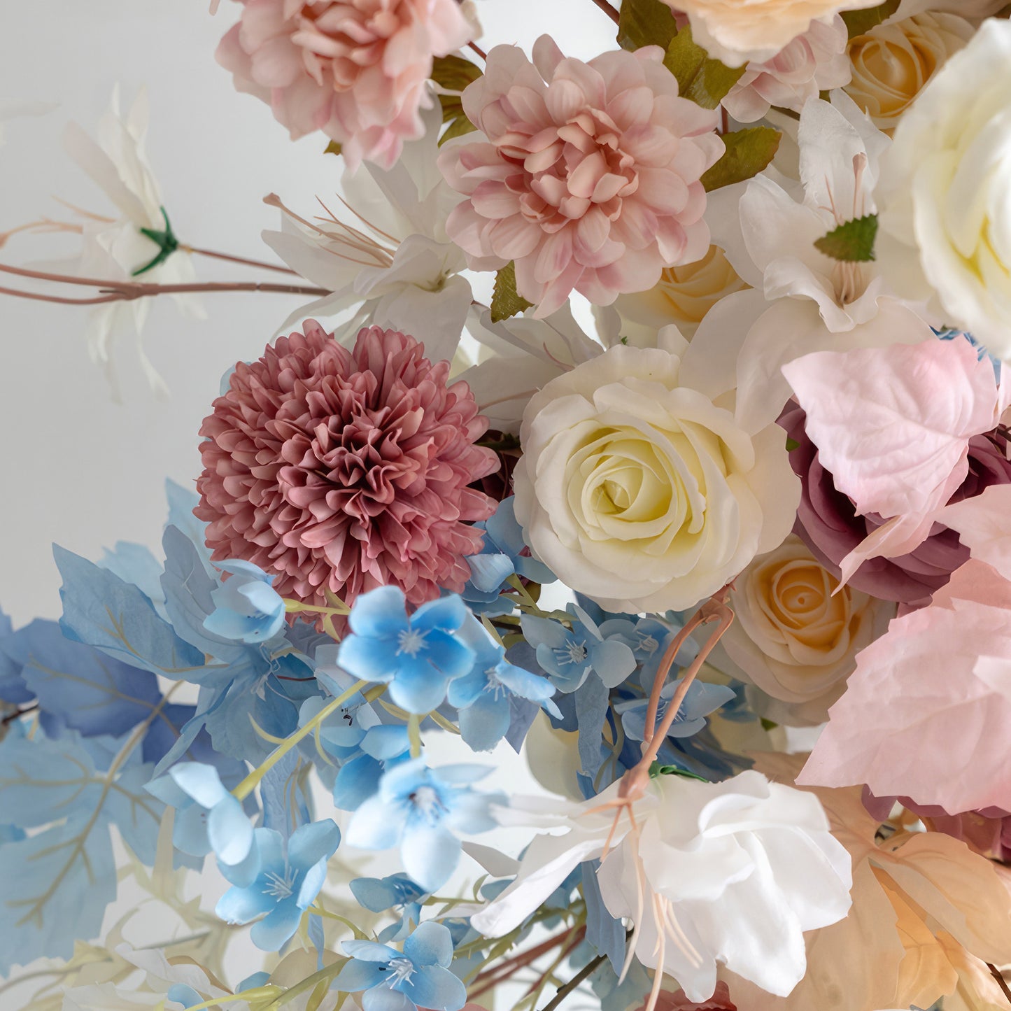 This close - up reveals an enchanting blend of flowers in soft pastel shades like pink, peach, white, and light blue. With roses, dahlias, and small blue blooms, it exudes a gentle, romantic style, ideal for enhancing weddings, parties, or any space needing a touch of elegance. 