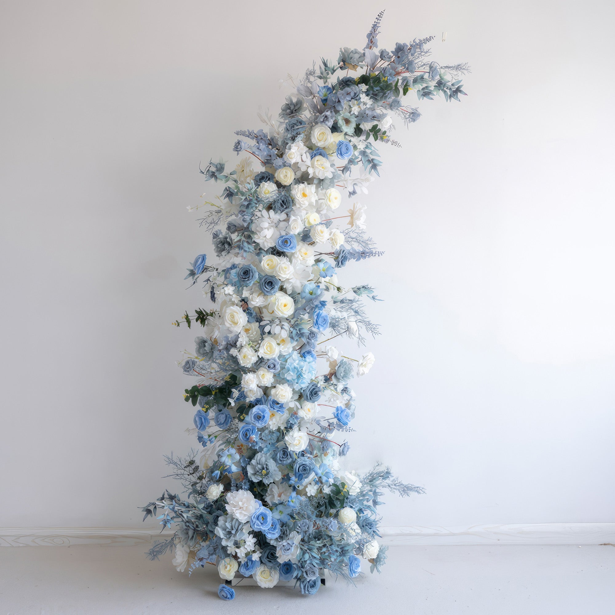 This is an elegant floral arch crafted from artificial flowers. It features a color combination of soft white and various shades of blue. With roses and other blooms, along with blue - toned foliage, it presents a serene, sophisticated, and dreamy style. 