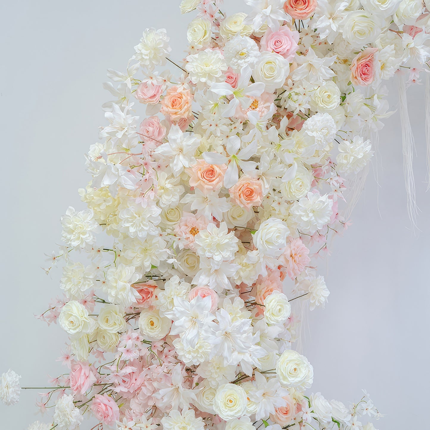 This image presents an artificial flower arrangement with roses, hydrangeas and other blossoms. Colors are soft white, light pink and peach. The style is romantic and elegant, exuding a gentle charm. 